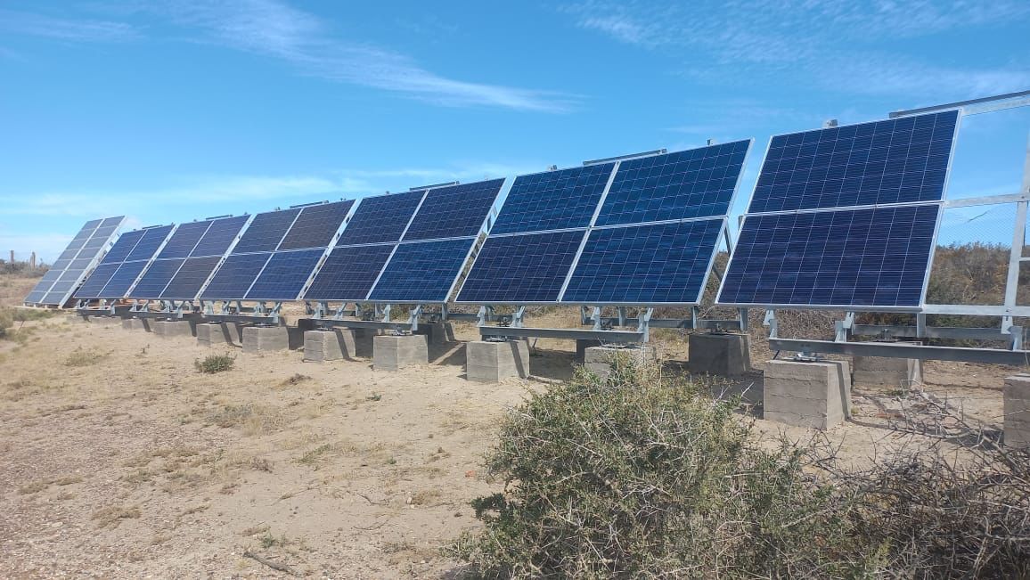 Paneles solares sobre bloques de hormigón en un entorno seco y al aire libre, bajo un cielo azul.