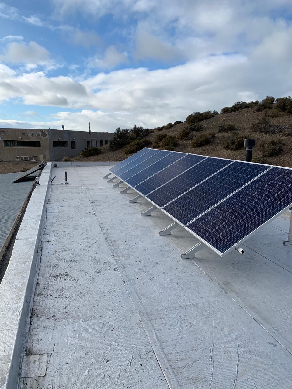 Paneles solares en un tejado plano contra un cielo nublado.