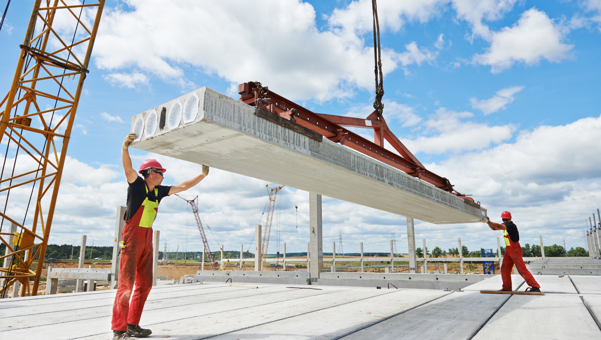 Construction workers lifting concrete slab with crane on a building site.