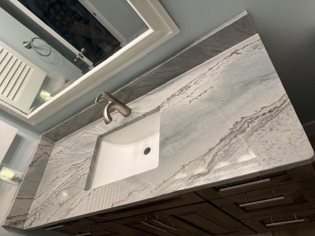 Oak cabinetry with a granite countertop, open shelves, and sage green beadboard backsplash in a kitchen.