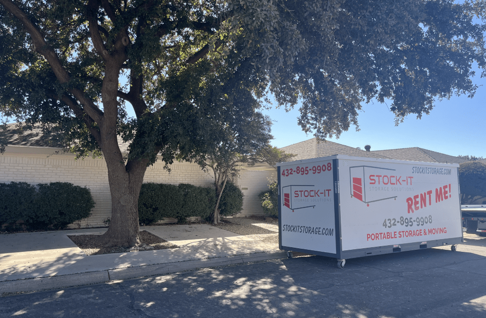 A white box with the word stock on it is parked in front of a tree.