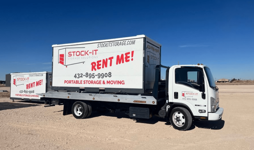 A truck that says stock-it rent me is parked in a dirt field.