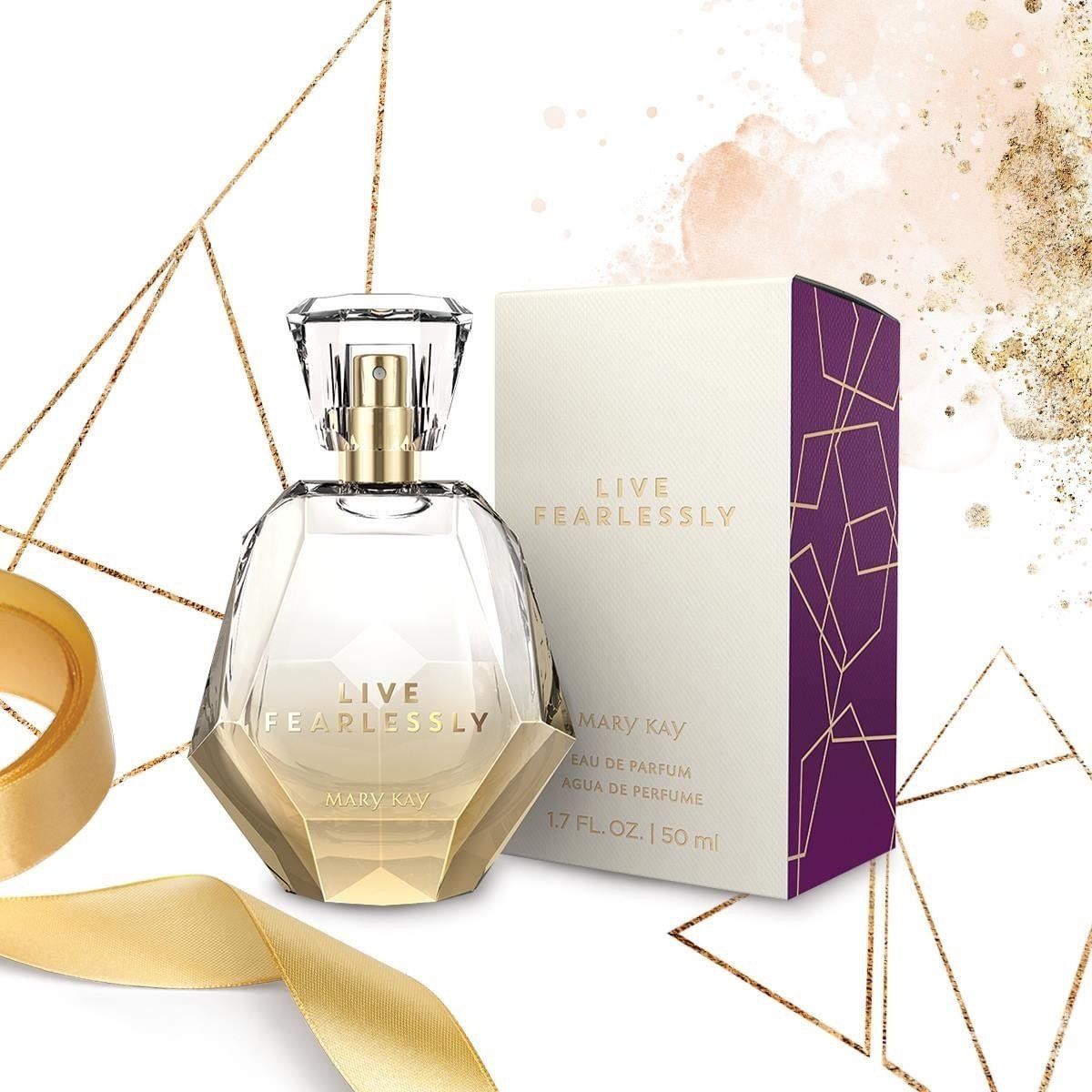 Perfume bottle and box. Gold-accented bottle next to white box with purple accents and gold text.