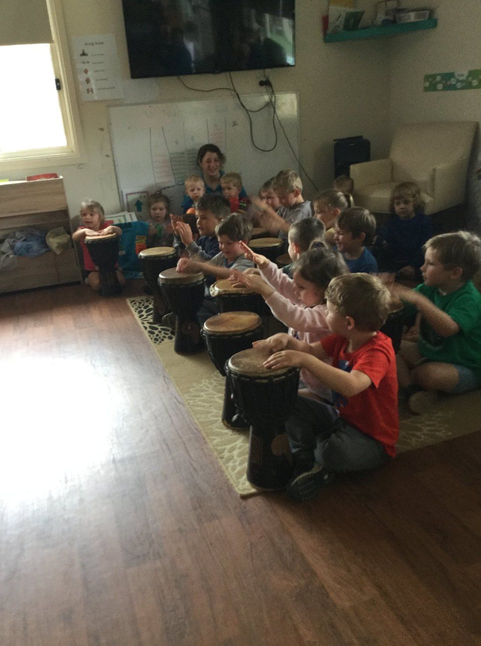 A Group of Children Are Sitting on the Floor Playing Drums — Earth Angels Child Care Centre in Tinonee, NSW