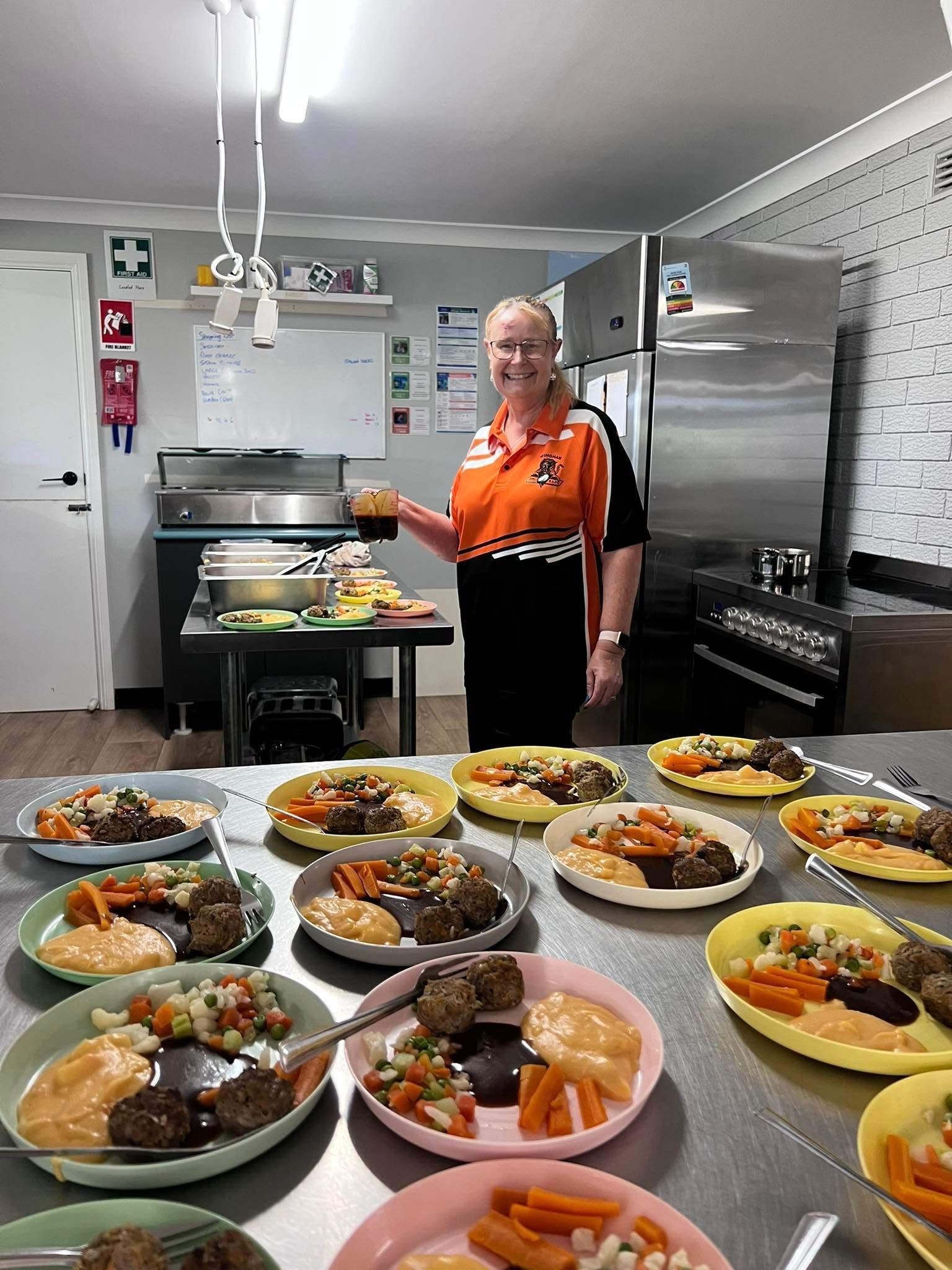 A Man is Standing in Front of a Table Filled With Plates of Food — Earth Angels Child Care Centre in Tinonee, NSW
