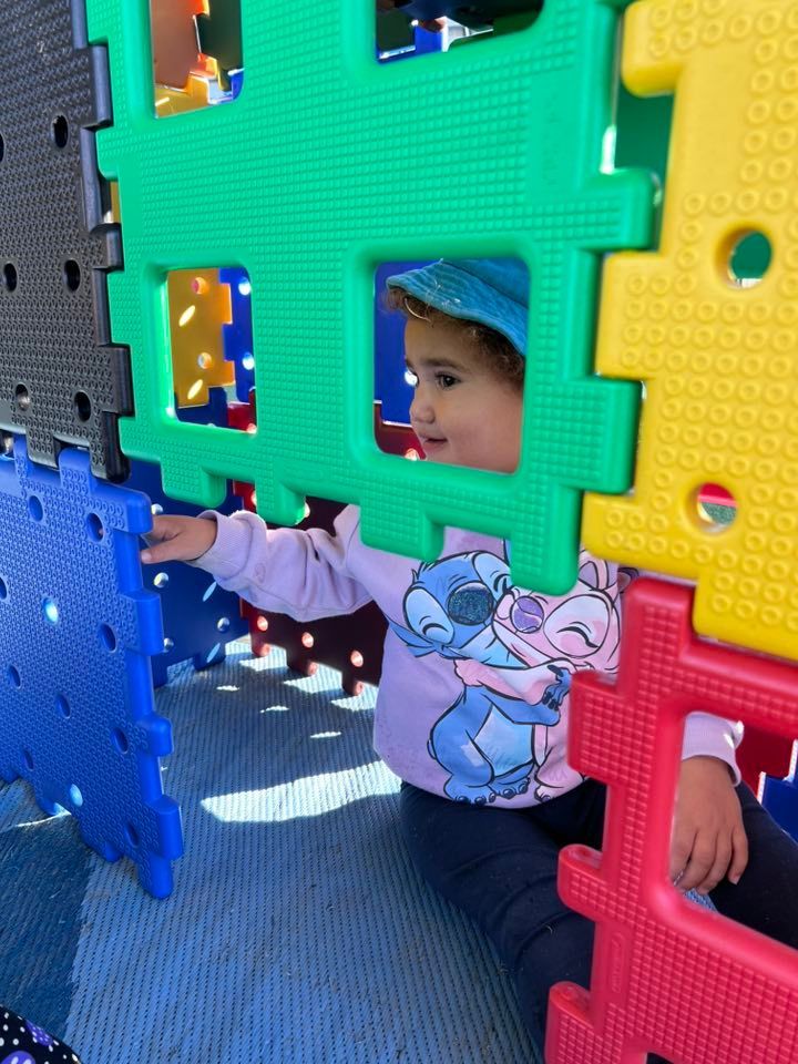 A Little Girl Wearing a Stitch Shirt is Playing in a Playground — Earth Angels Child Care Centre in Tinonee, NSW