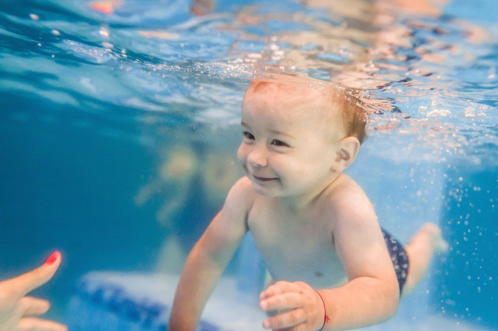 A Baby is Swimming Underwater in a Swimming Pool — Earth Angels Child Care Centre in Tinonee, NSW