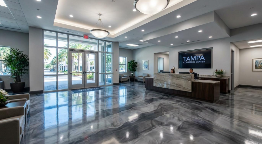 Modern hotel lobby with marble floors, reception desk, seating, and glass entrance doors