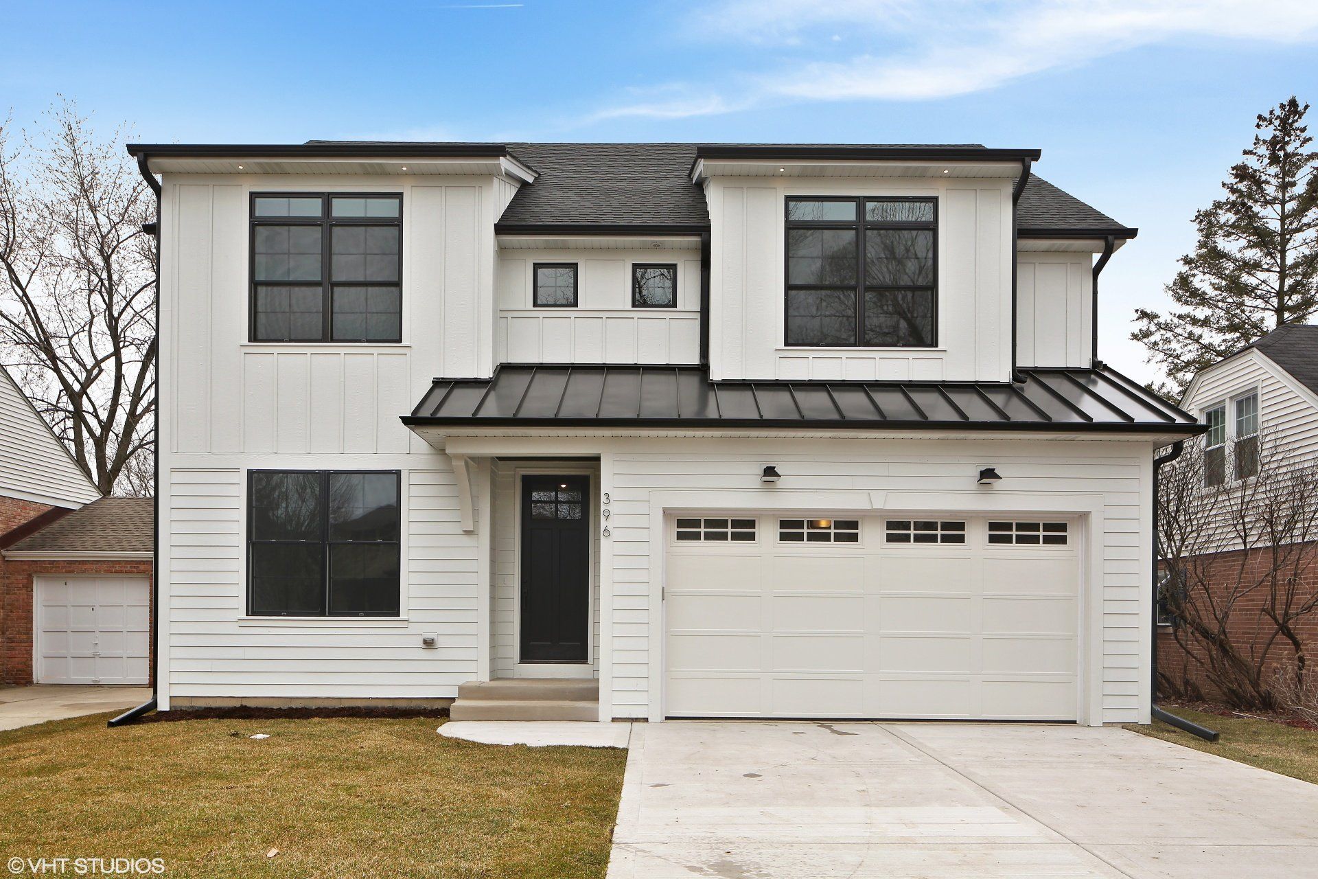 A white house with a black roof and a black garage door