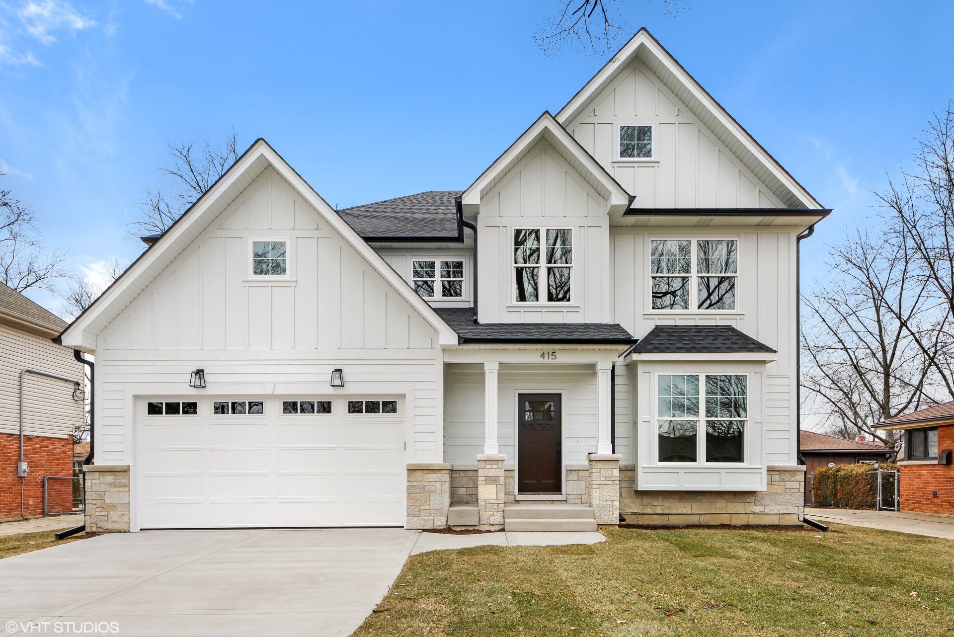 A white house with a black roof and a white garage door.