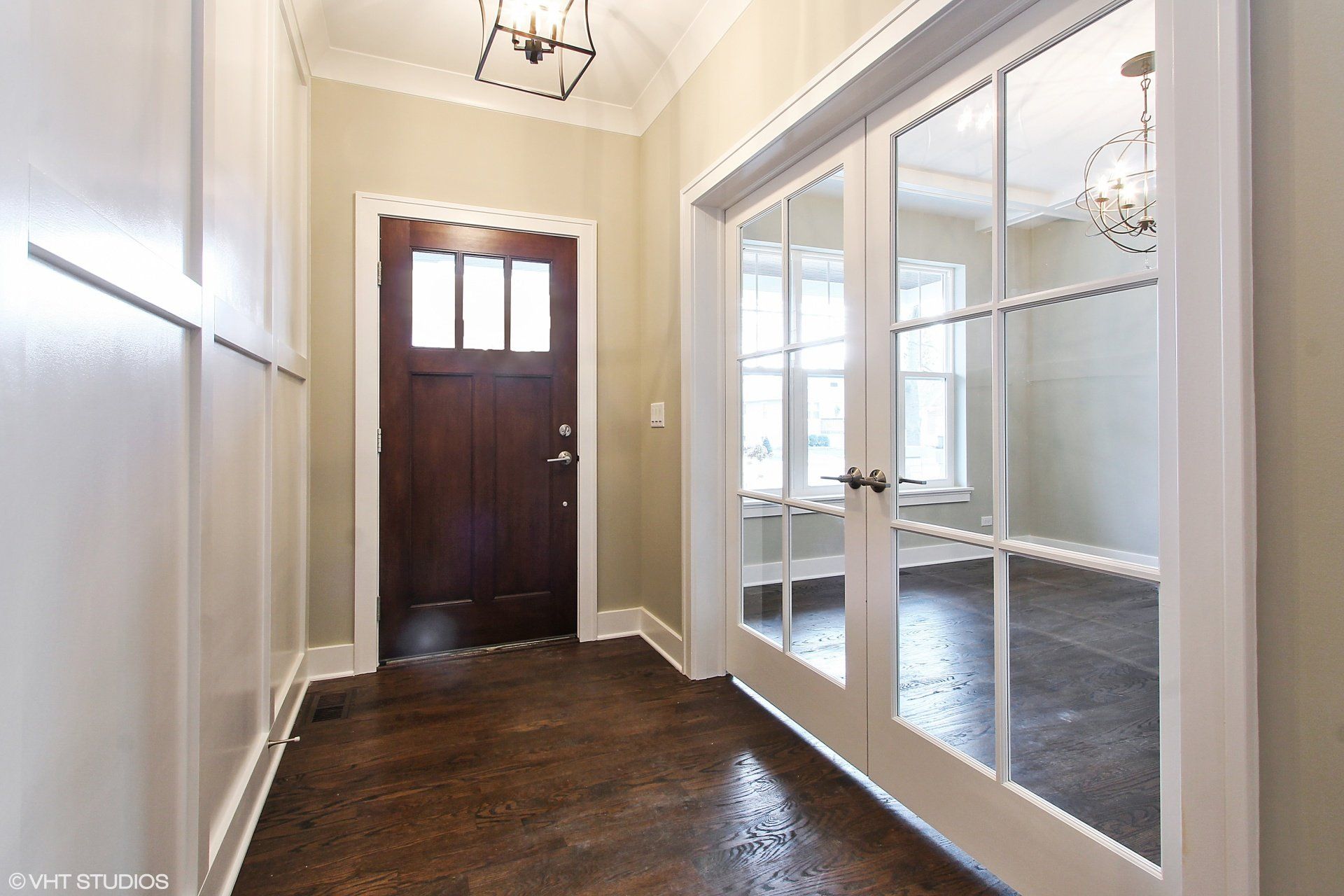 A hallway with a wooden door and glass doors