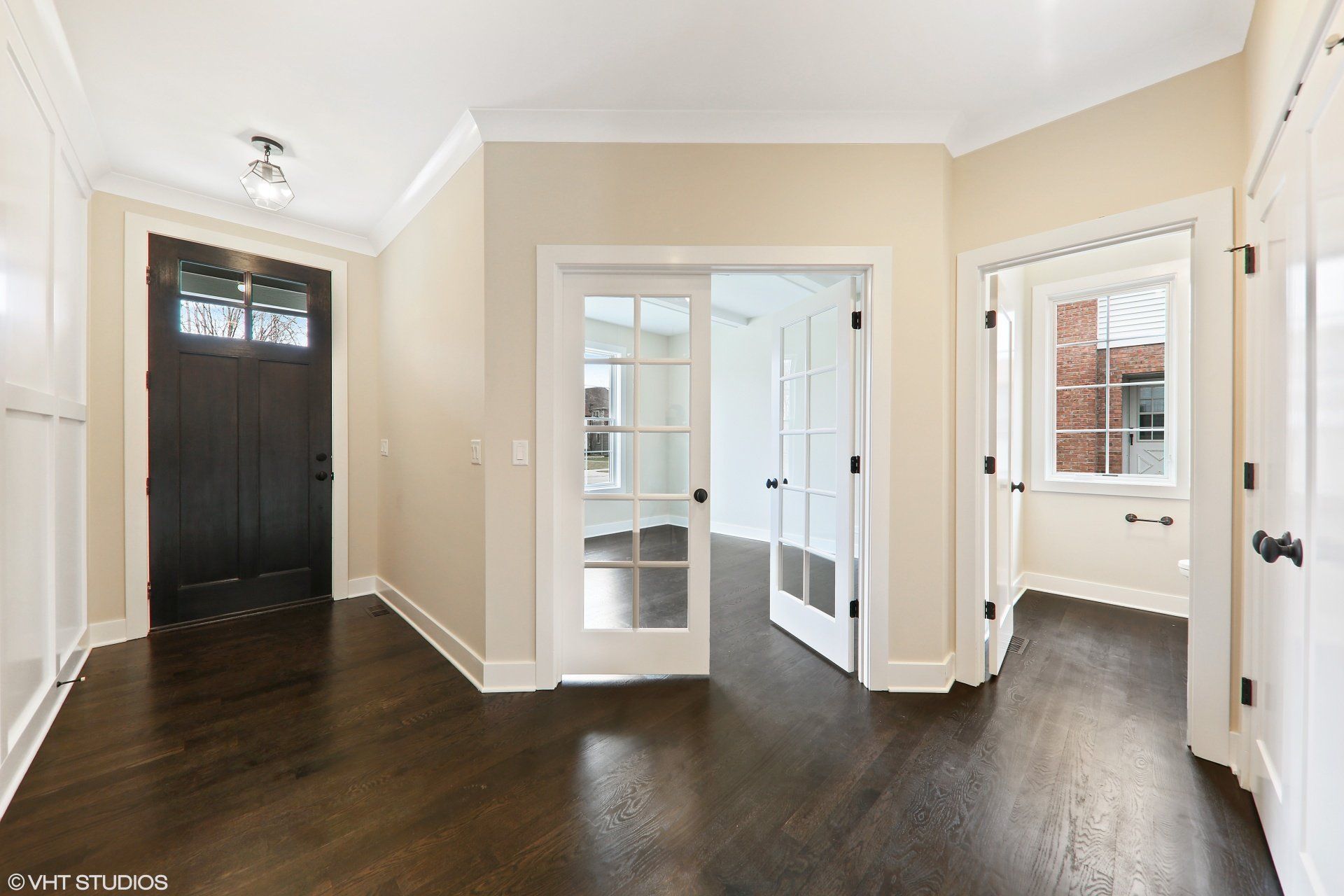 An empty hallway with hardwood floors and a black door