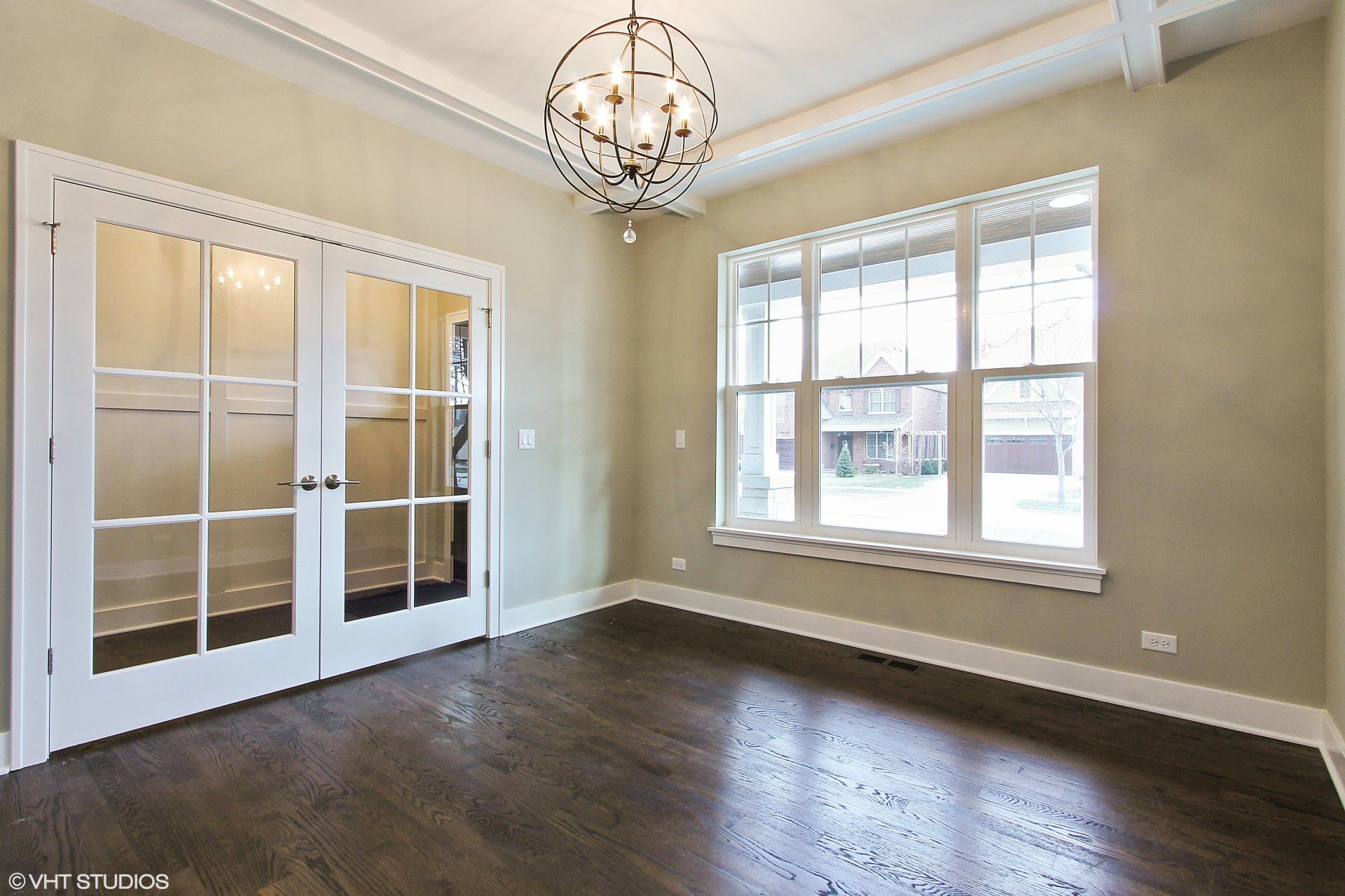 An empty room with a chandelier hanging from the ceiling