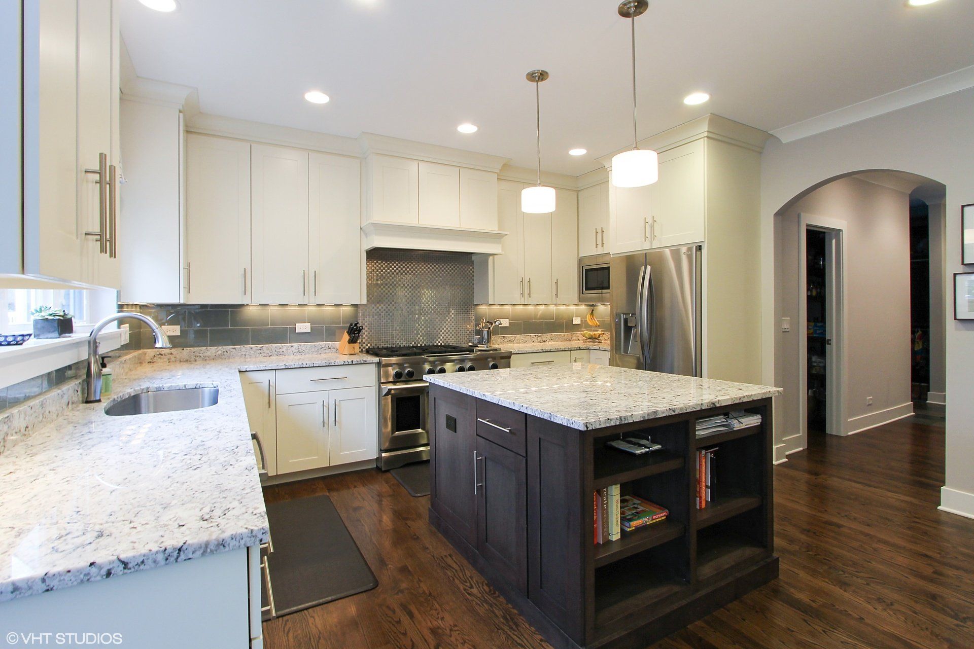 A kitchen with white cabinets , granite counter tops , stainless steel appliances and a large island.