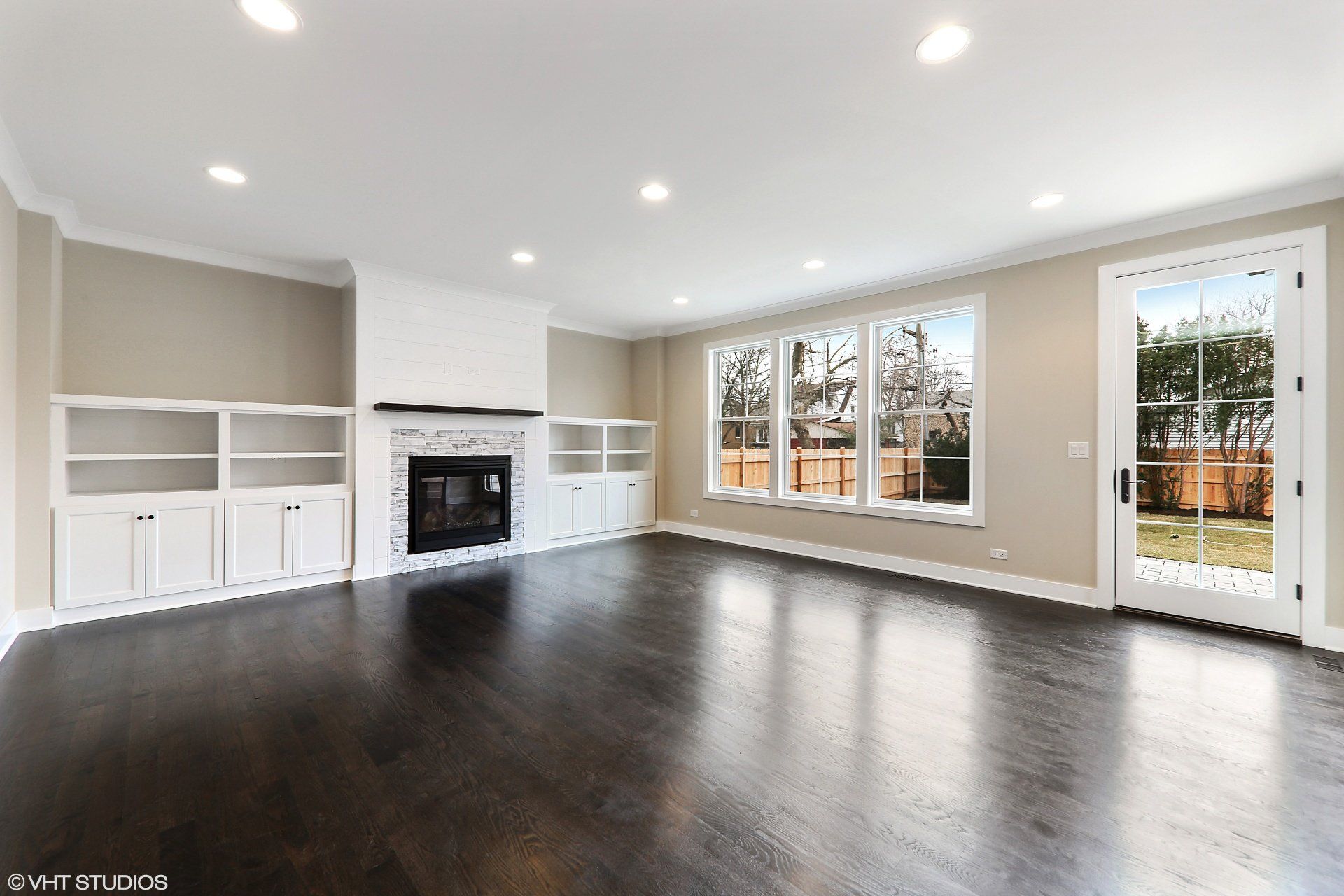 An empty living room with a fireplace and lots of windows