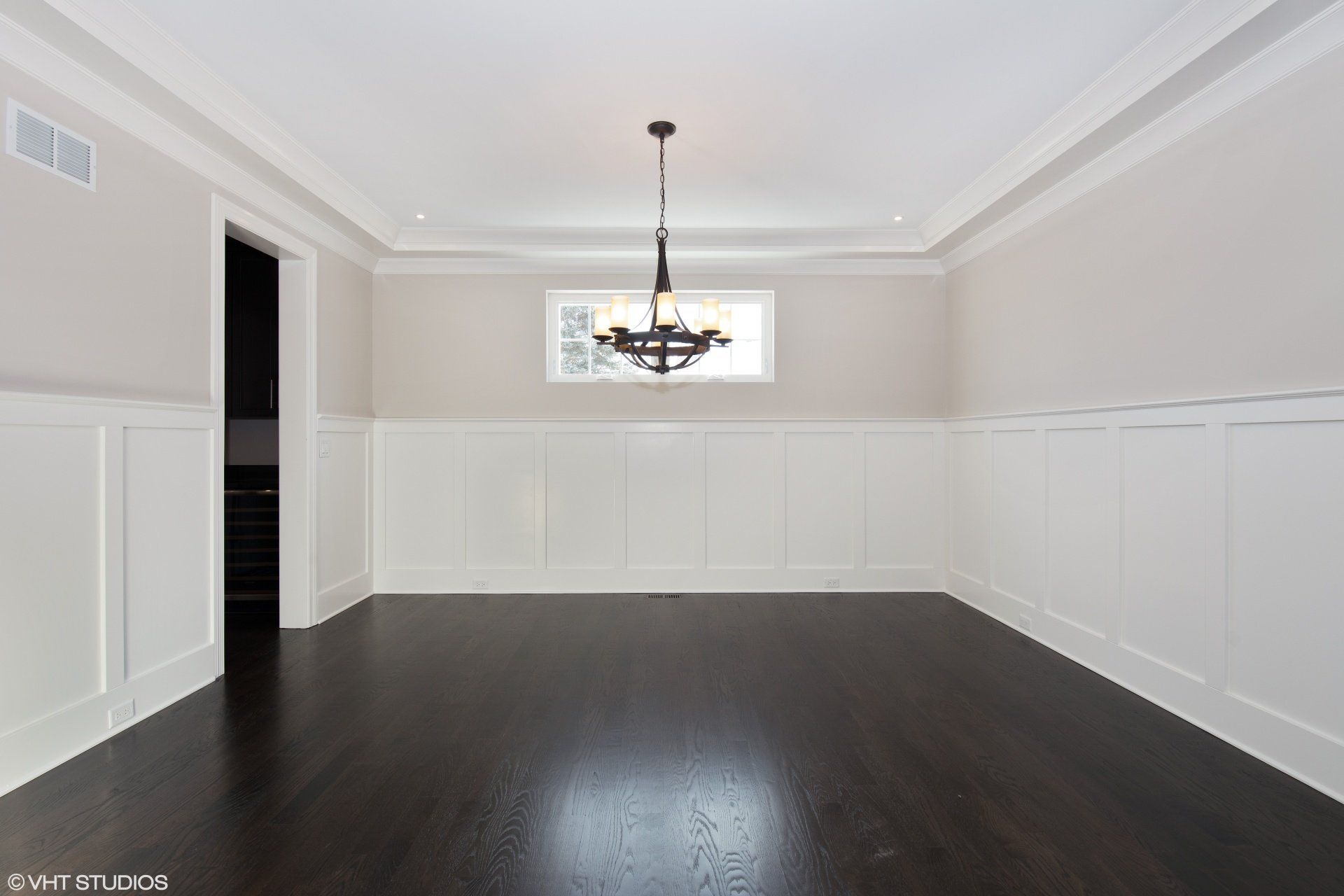 An empty dining room with a chandelier hanging from the ceiling