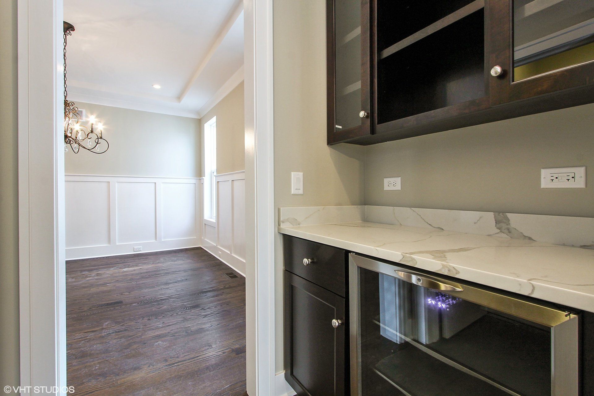 A kitchen with a wine cooler and marble counter tops.