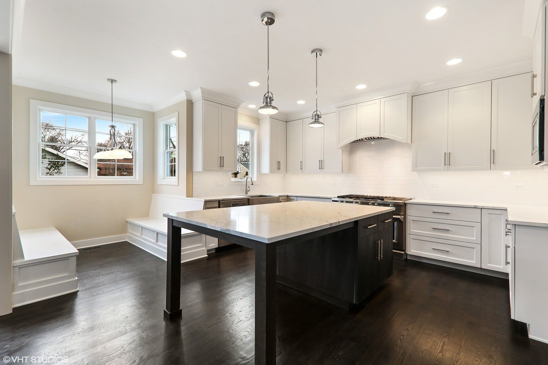 A kitchen with white cabinets and a large island in the middle