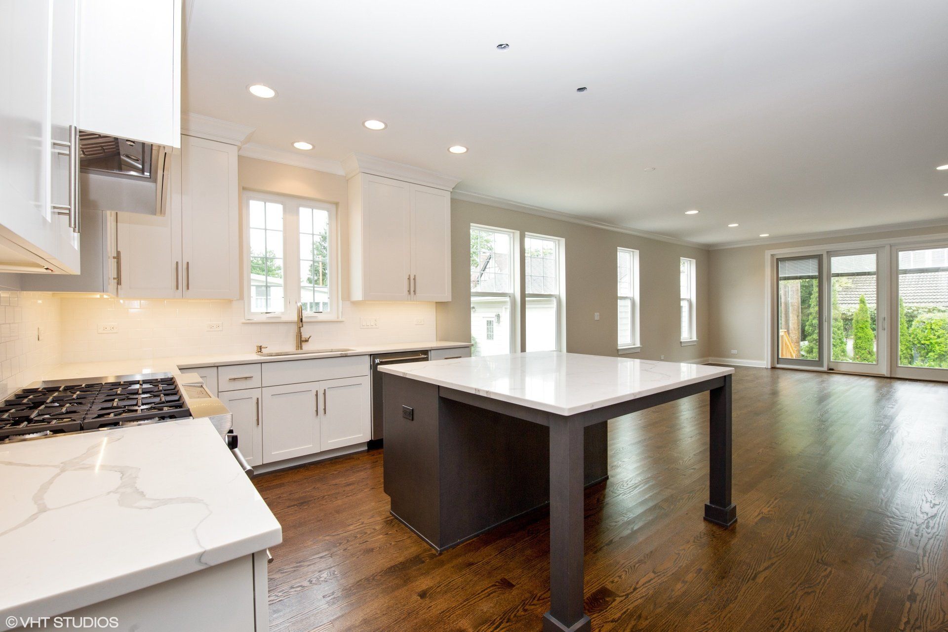 An empty kitchen with white cabinets and a large island in the middle.