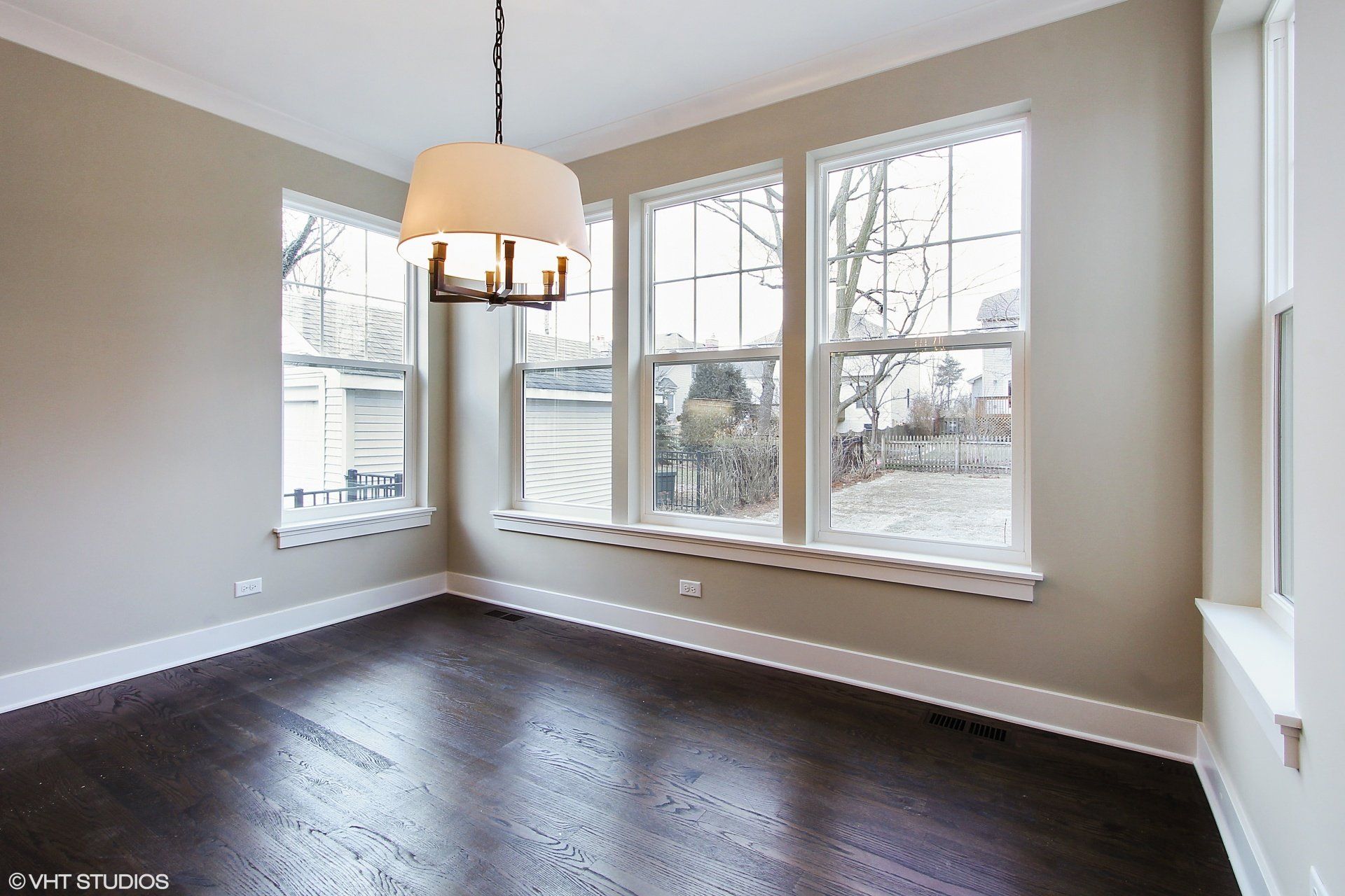 An empty room with a chandelier and lots of windows