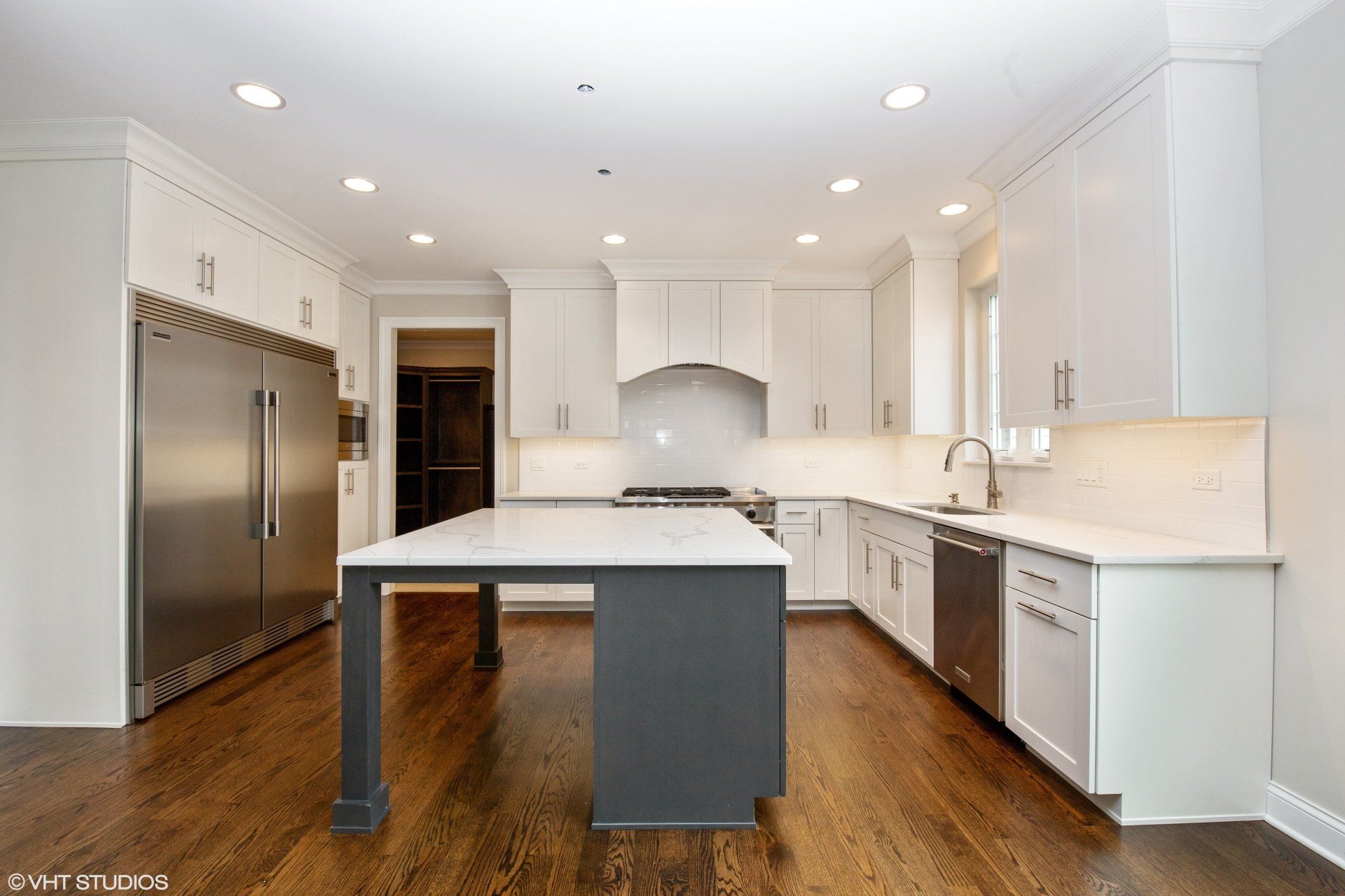 A kitchen with white cabinets , stainless steel appliances , and a large island.