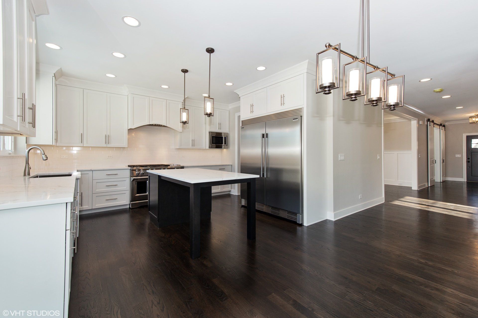 A kitchen with white cabinets , stainless steel appliances , and a large island.