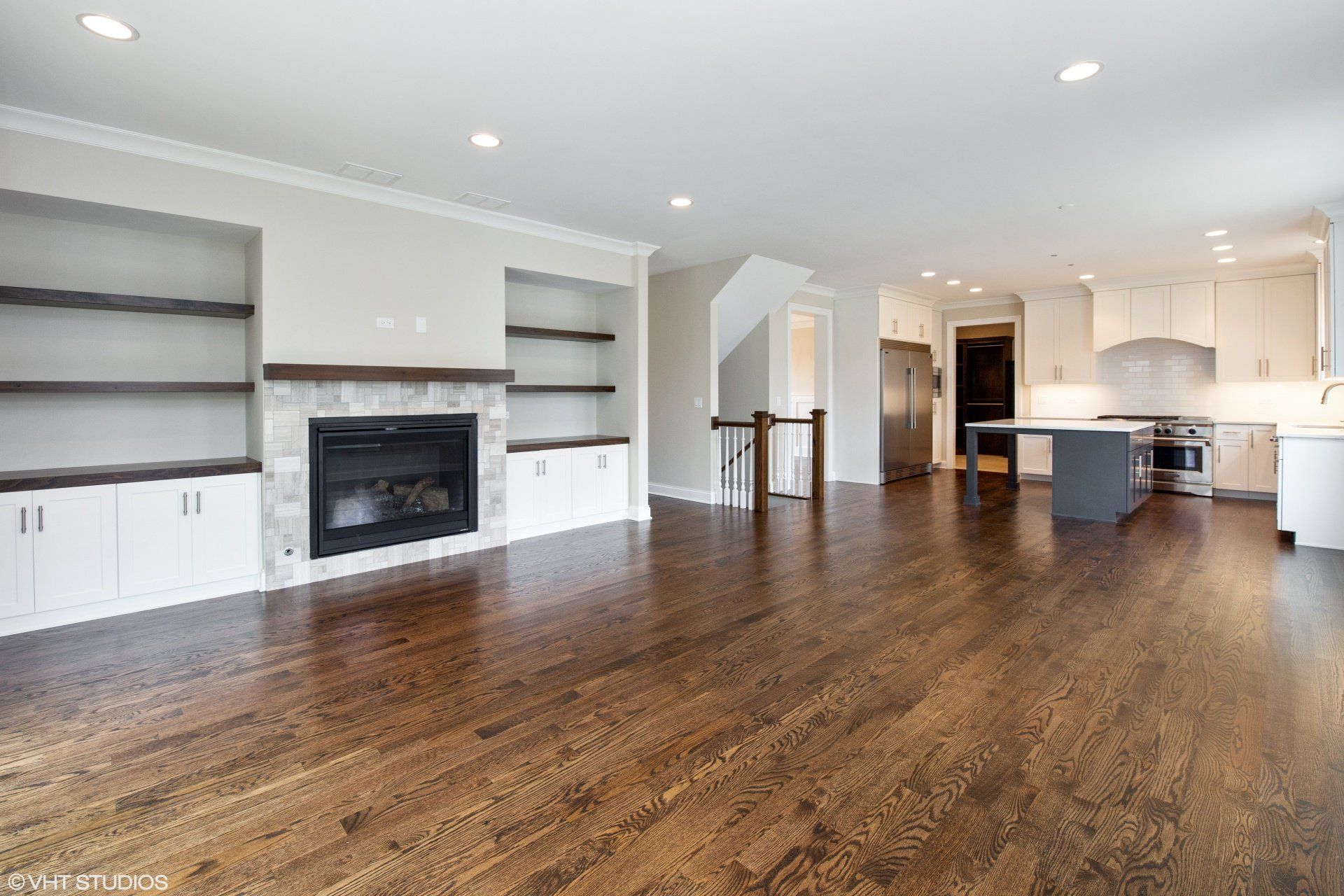 An empty living room with hardwood floors and a fireplace.