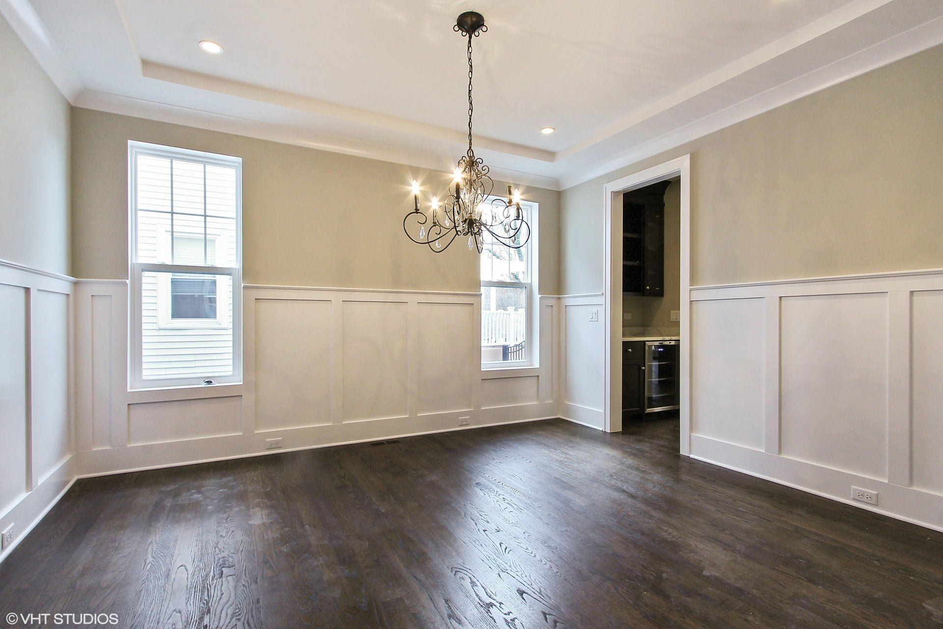 An empty dining room with hardwood floors and a chandelier