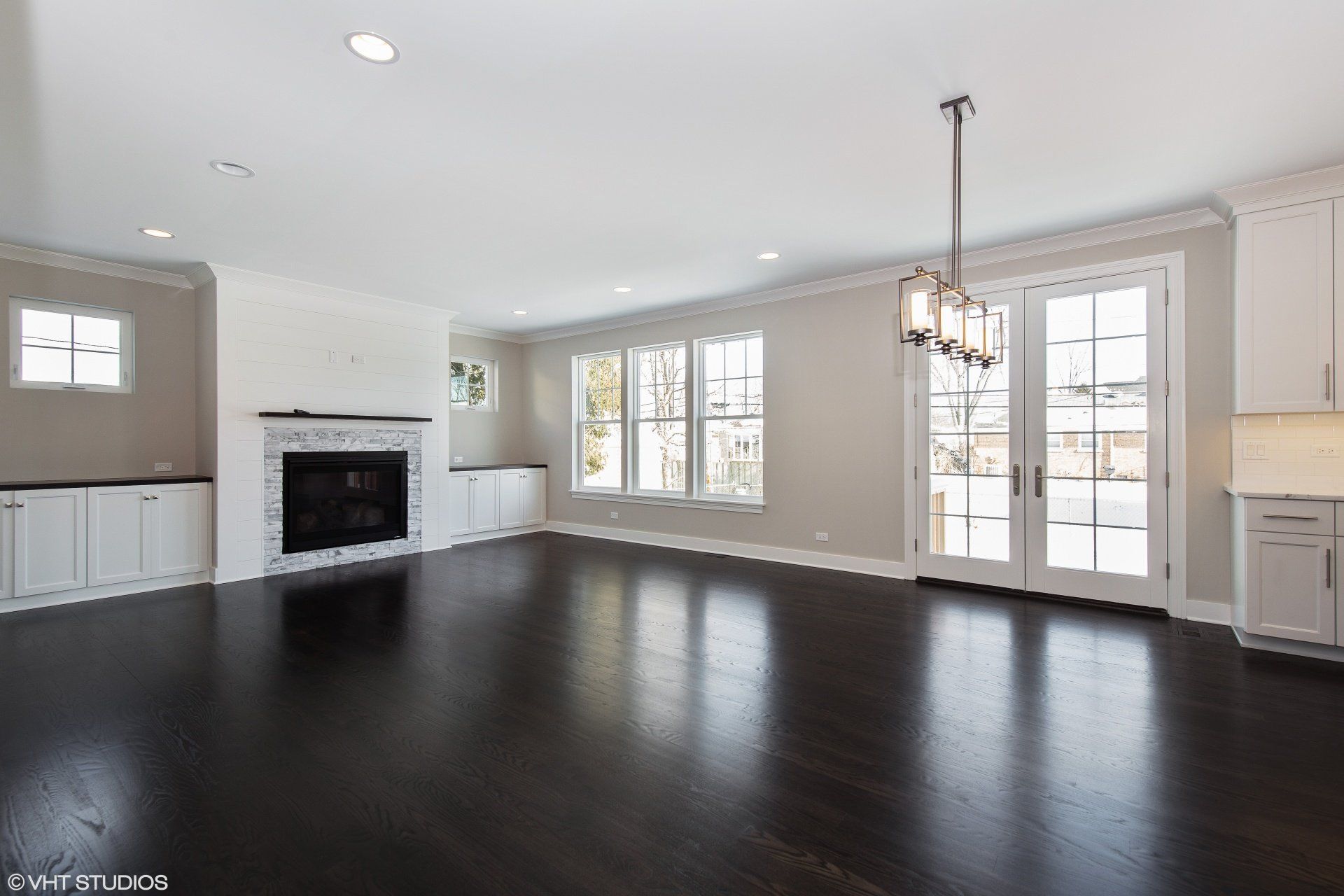 An empty living room with a fireplace and a chandelier.