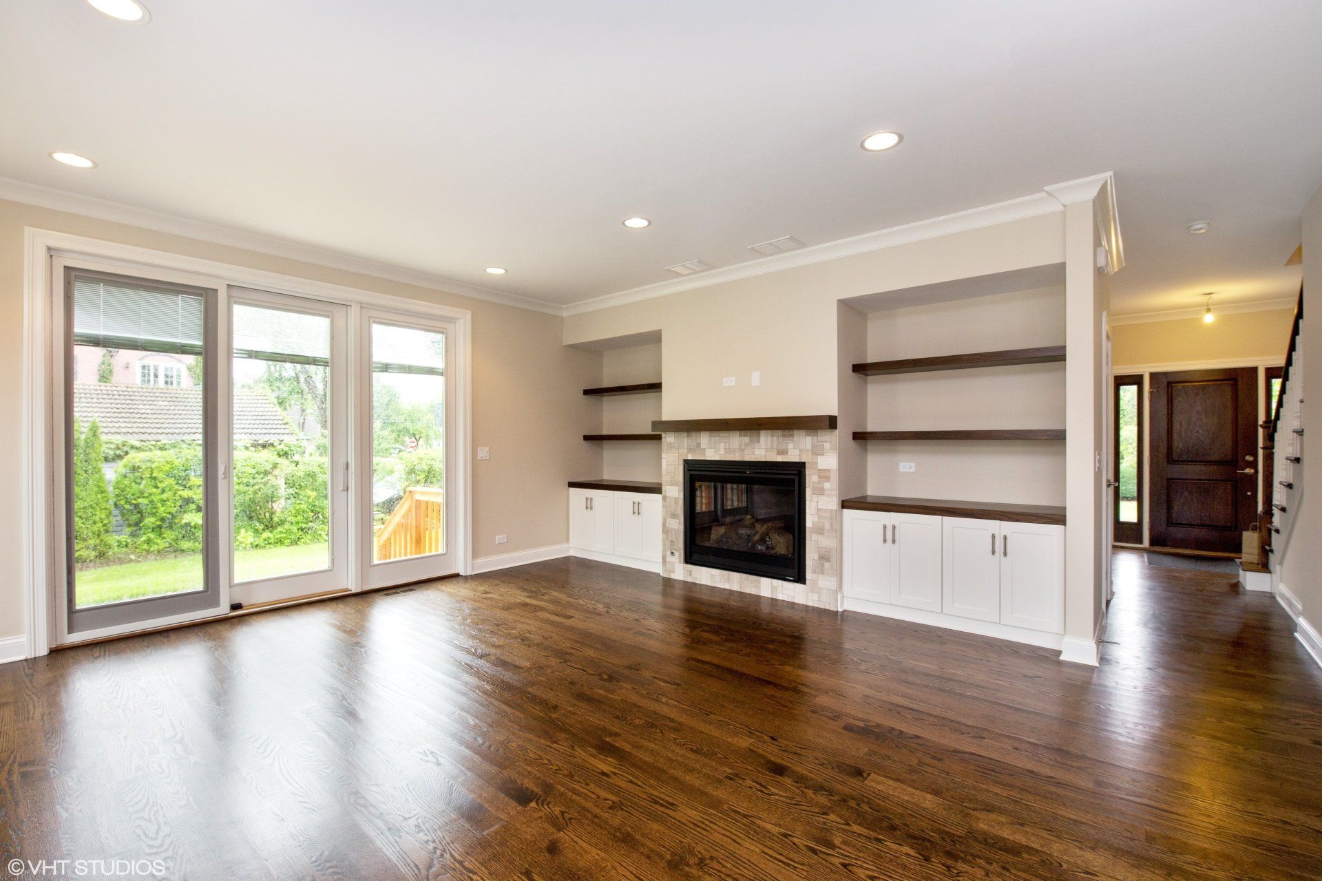 An empty living room with hardwood floors and a fireplace.