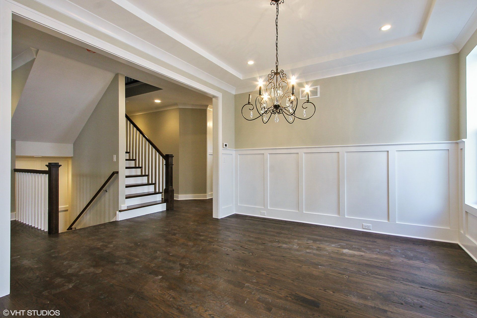 An empty dining room with stairs and a chandelier
