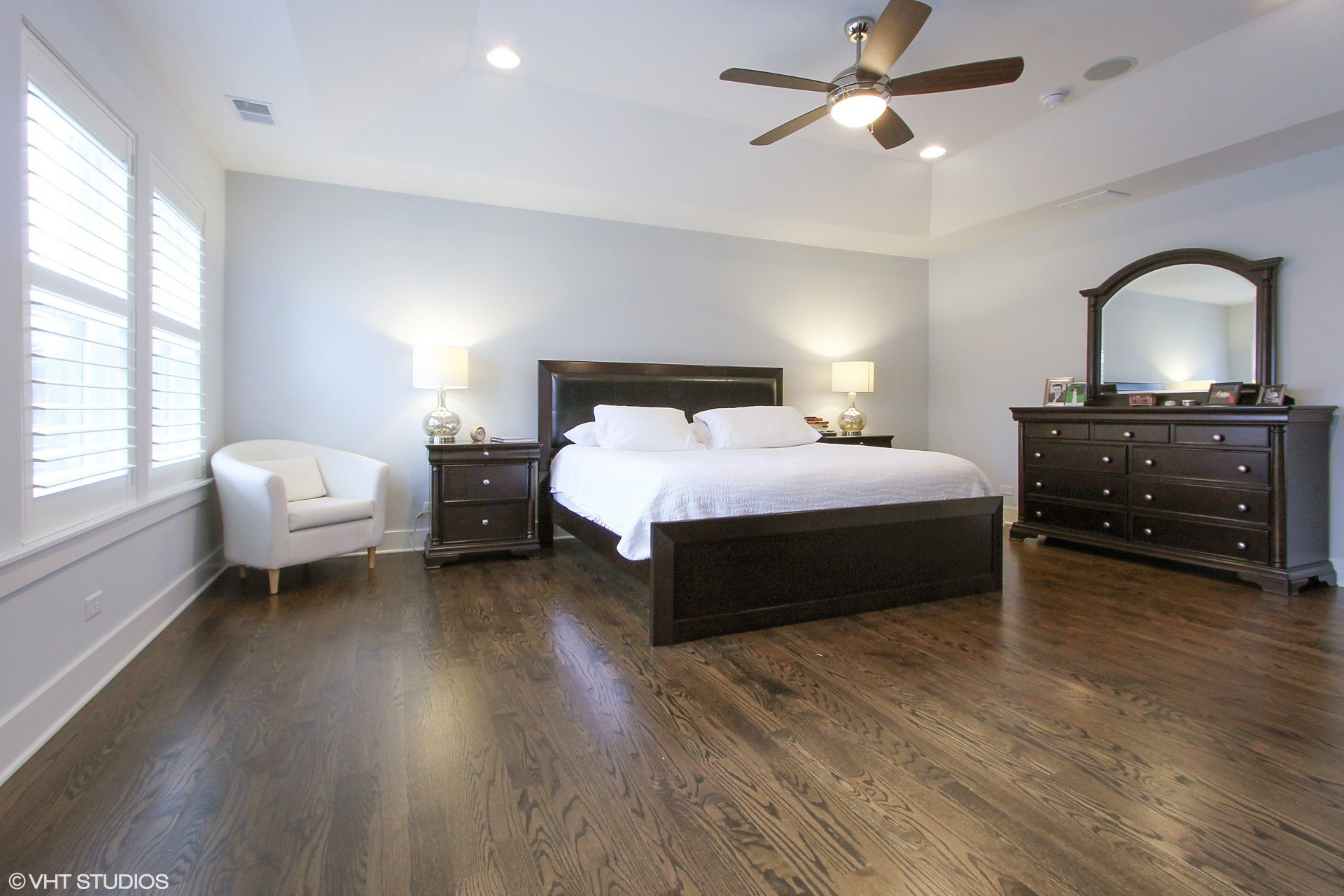 A bedroom with a bed , dresser , mirror and chair