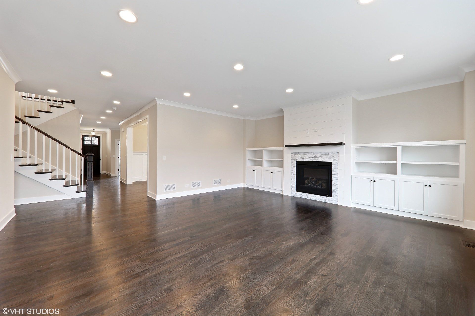 An empty living room with hardwood floors and a fireplace.