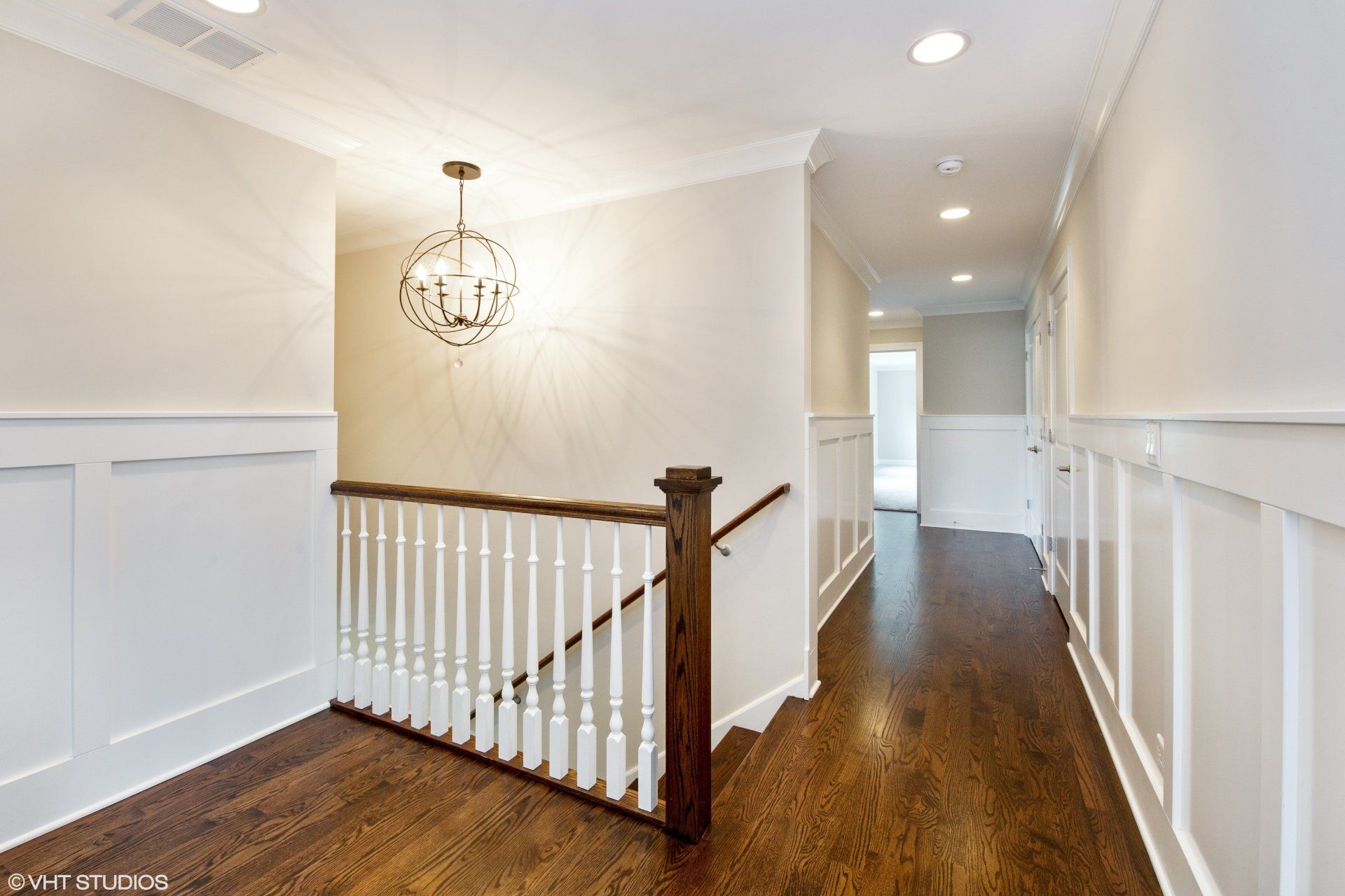A hallway with stairs and a chandelier in a house.