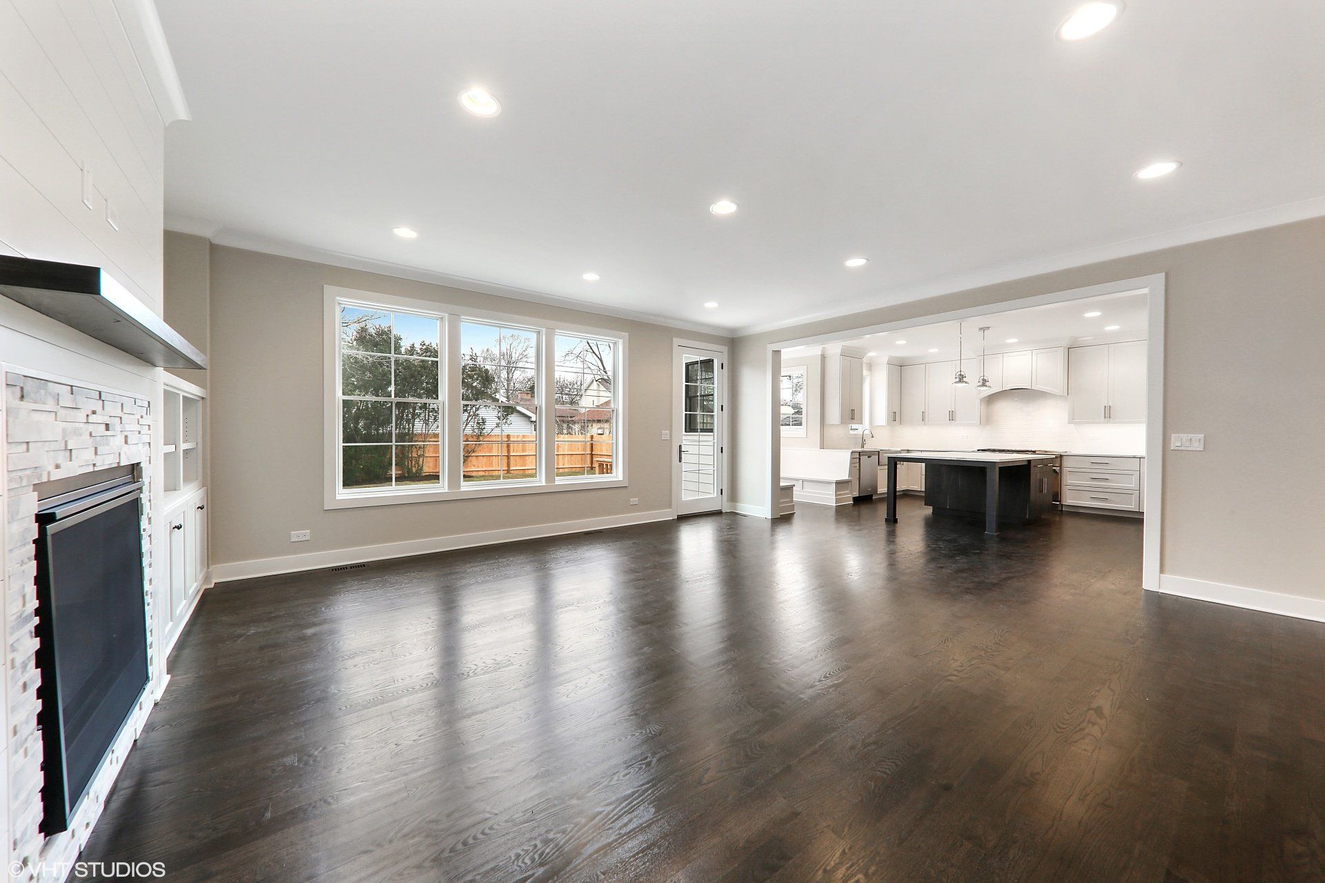 An empty living room with hardwood floors and a fireplace.
