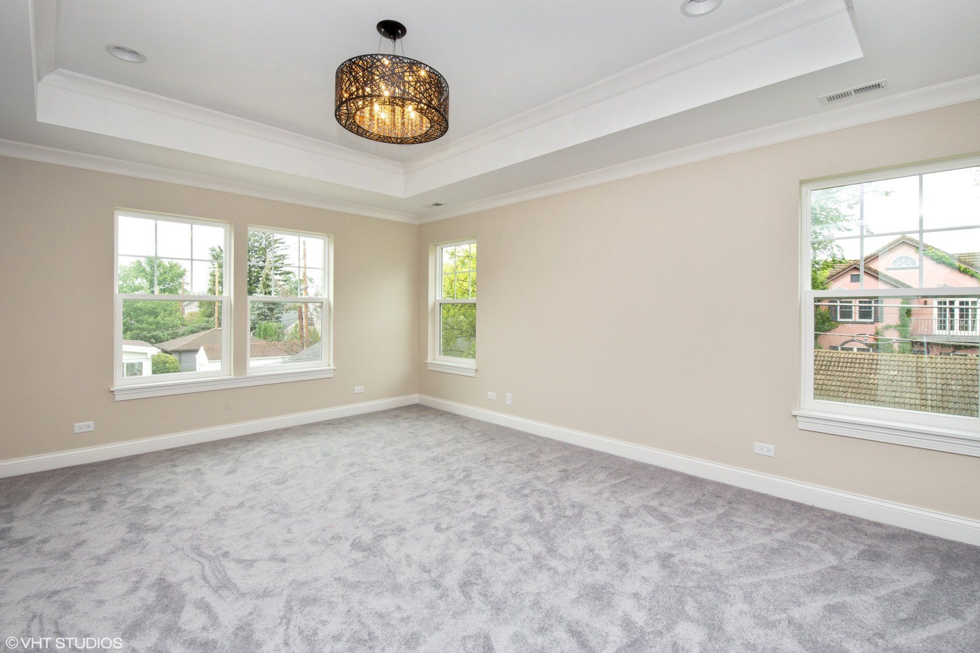 An empty bedroom with a lot of windows and a chandelier.