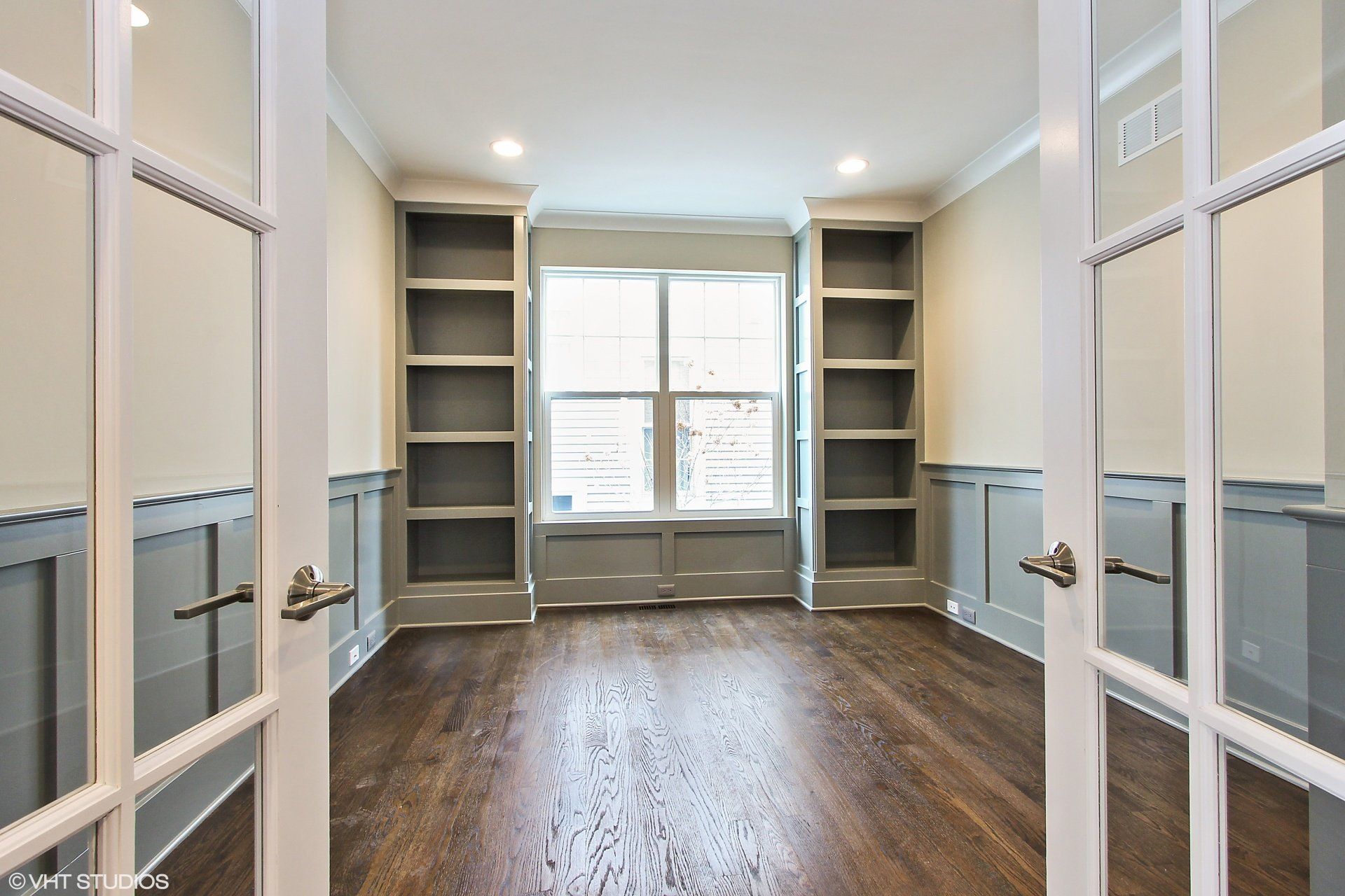 An empty room with hardwood floors and french doors