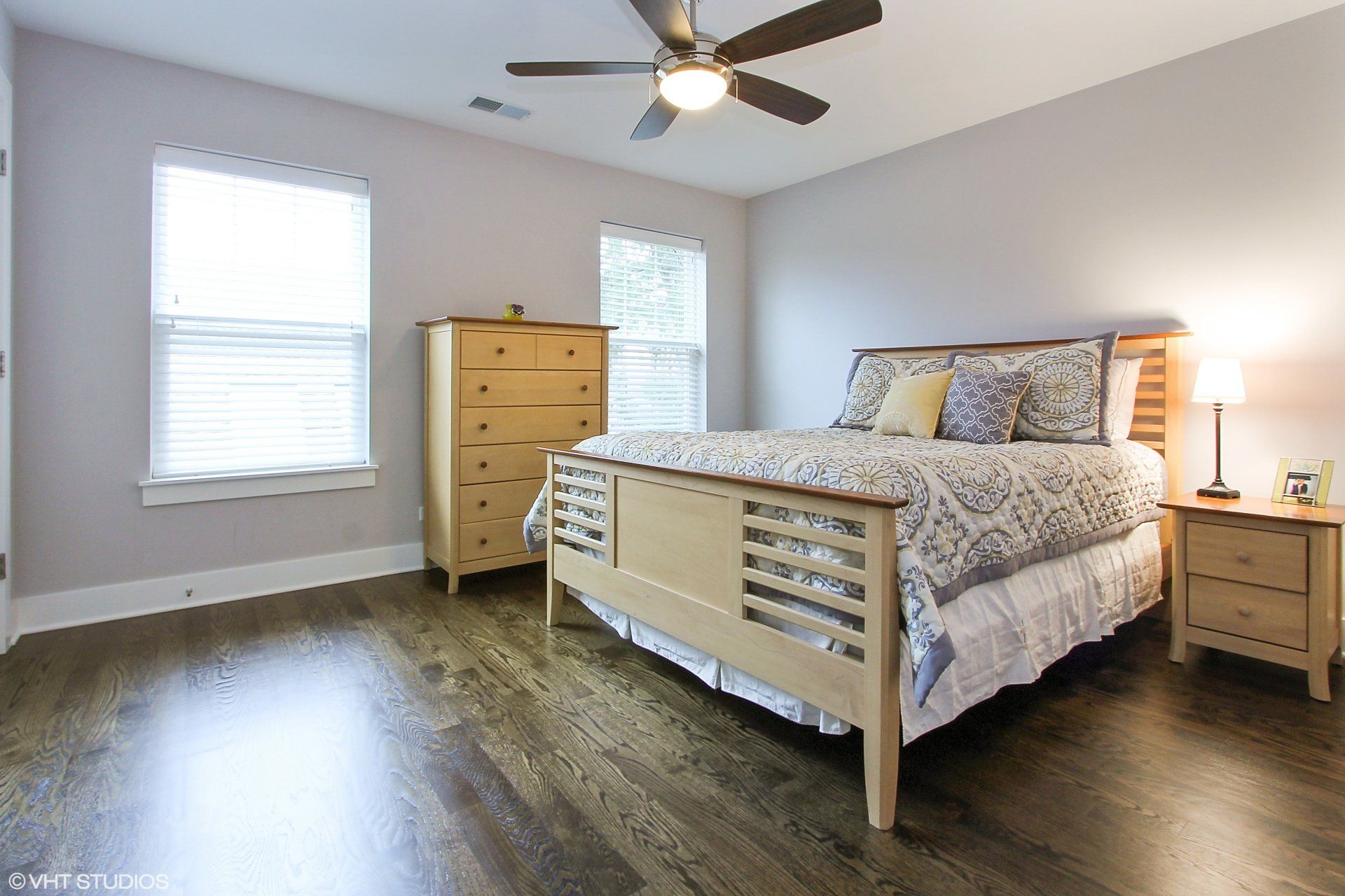 A bedroom with a bed , dresser , nightstand and ceiling fan.