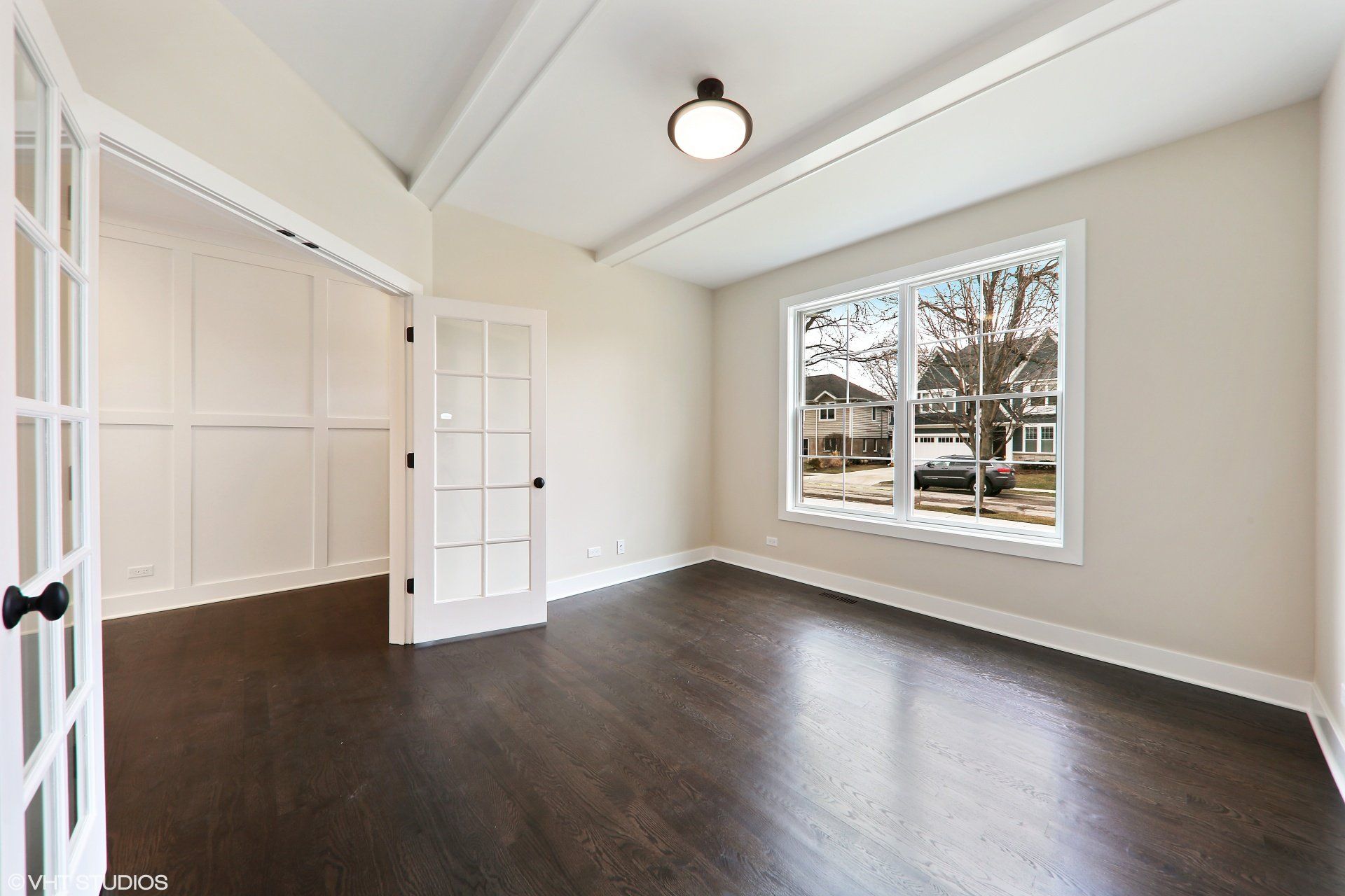 A large empty room with a lot of windows and hardwood floors.