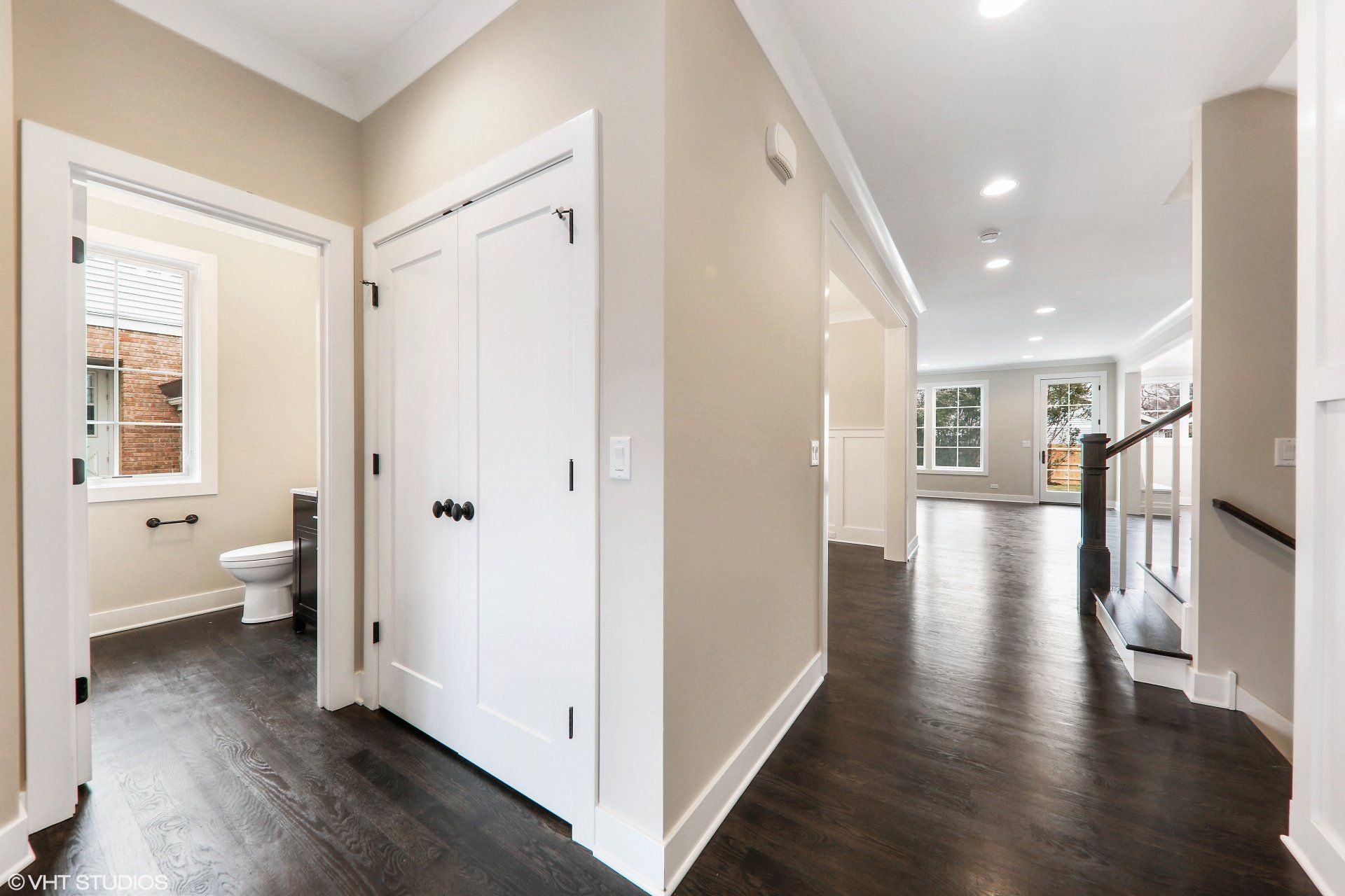 A hallway in a house with hardwood floors and a toilet.