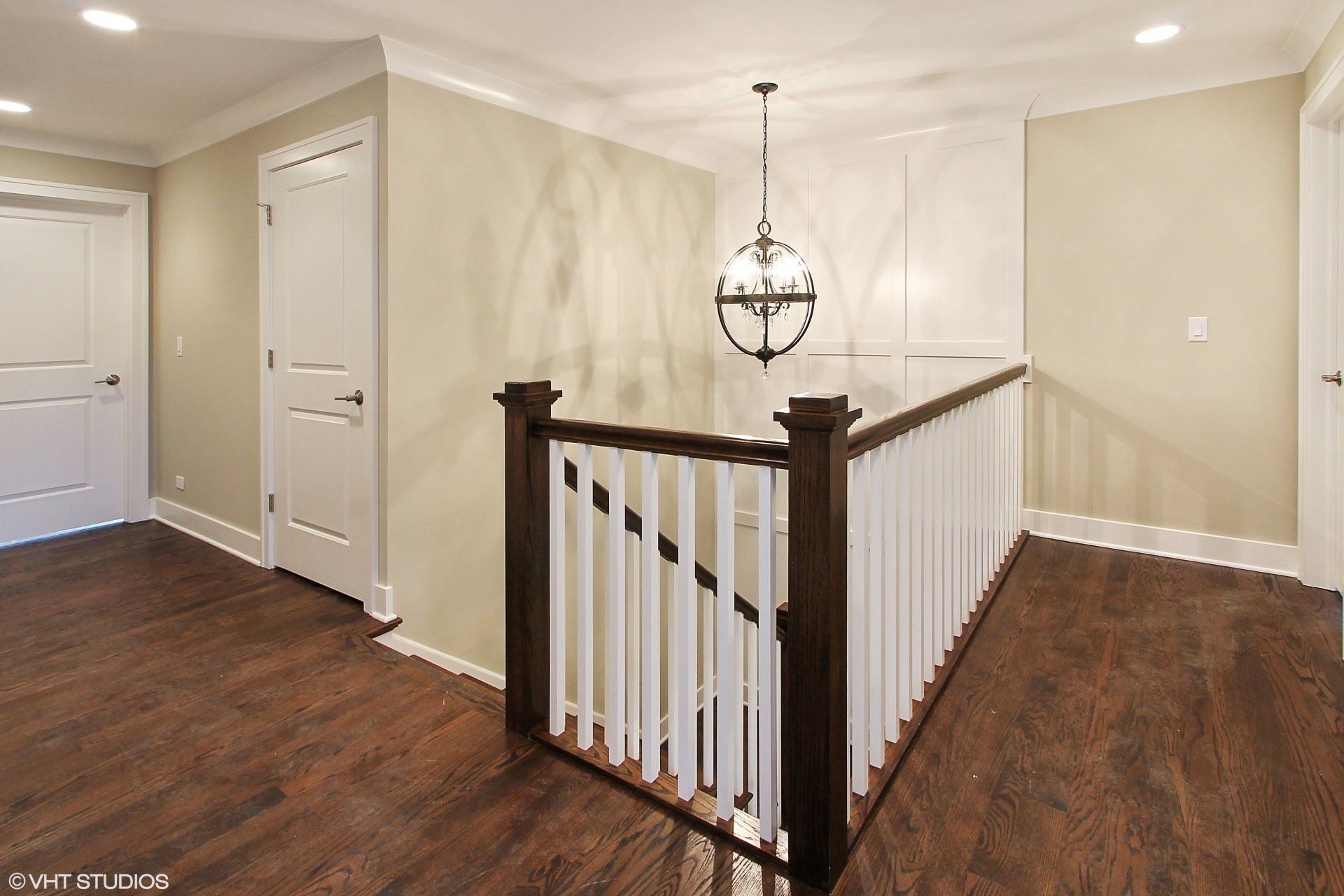A staircase with a wooden railing and a chandelier hanging from the ceiling.