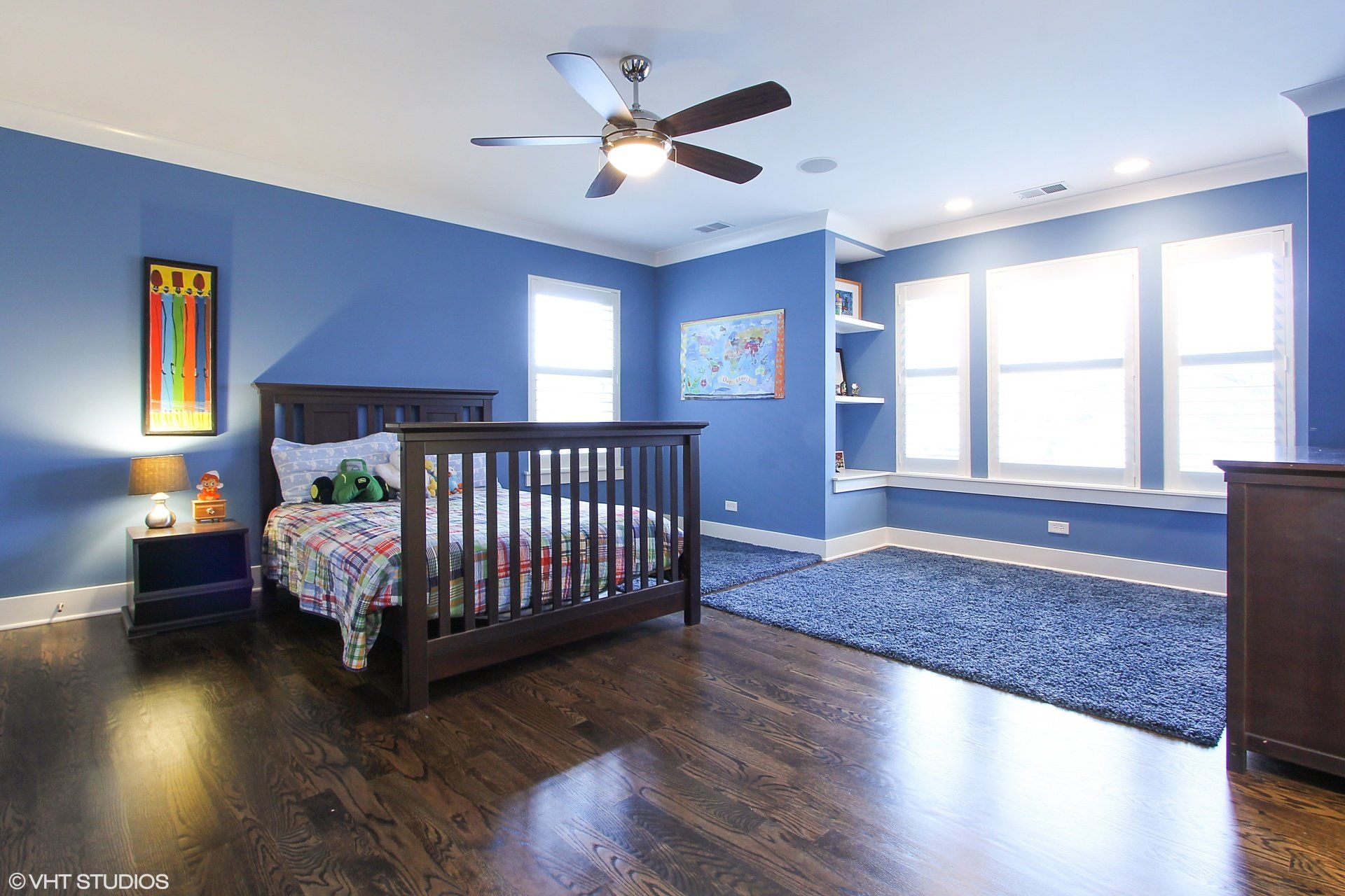 A bedroom with blue walls and a ceiling fan