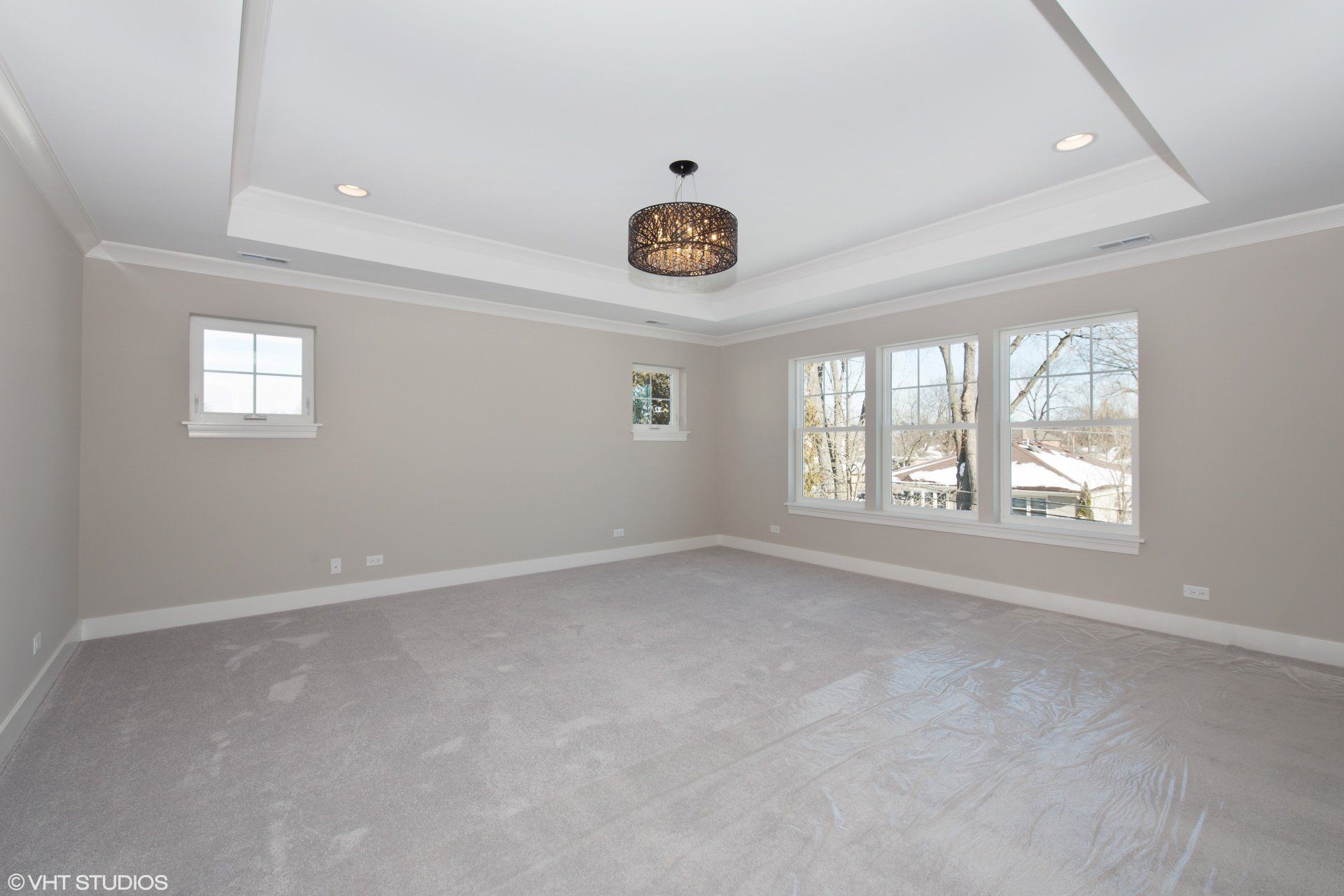 A large empty room with a lot of windows and a chandelier hanging from the ceiling.