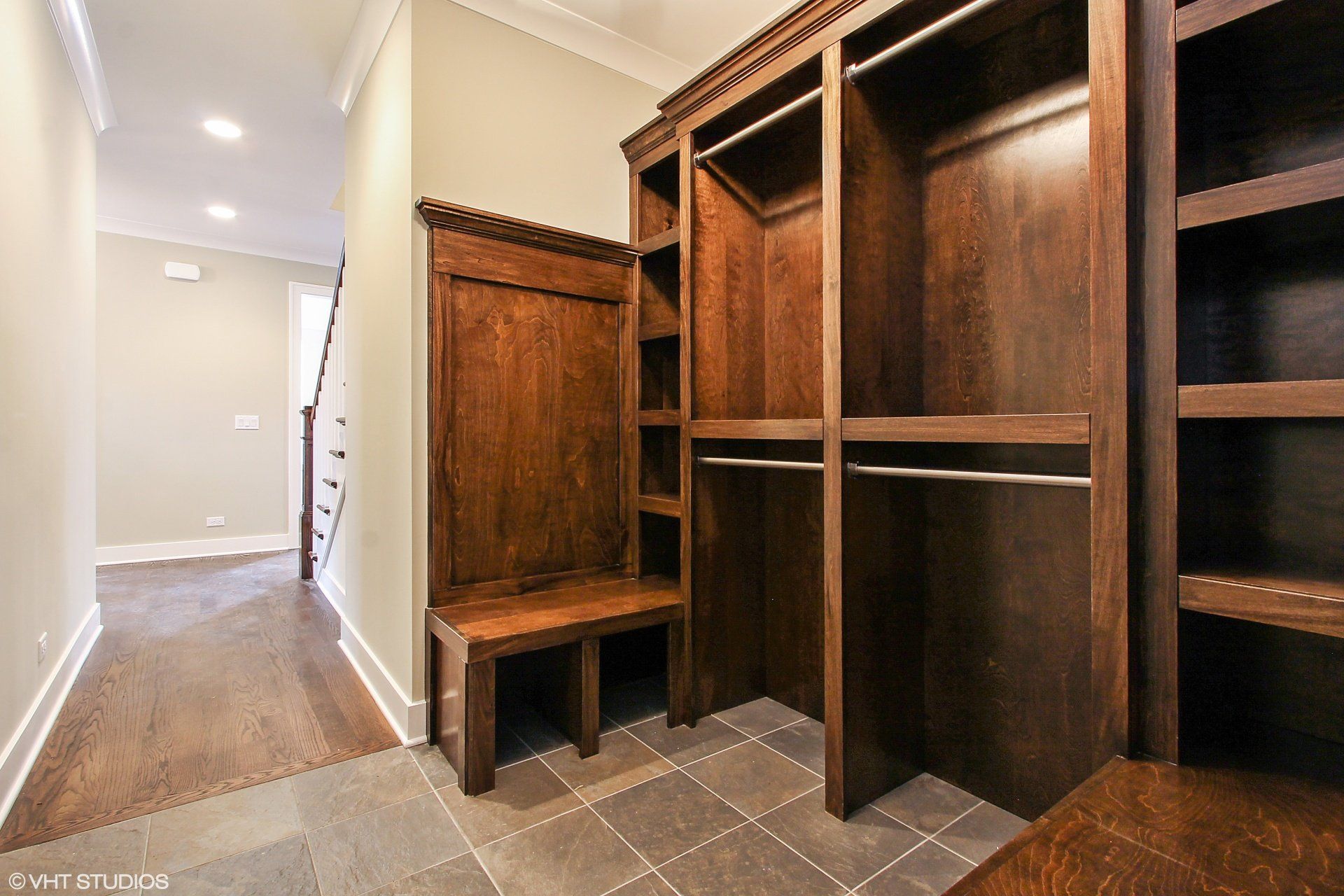 A walk in closet with wooden shelves and a bench