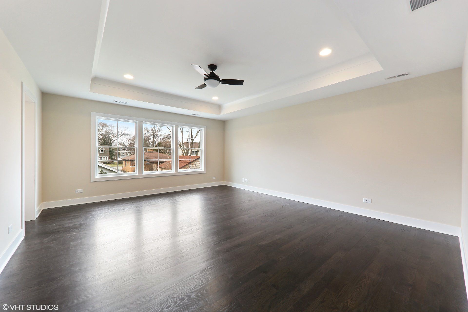 A large empty room with hardwood floors and a ceiling fan.