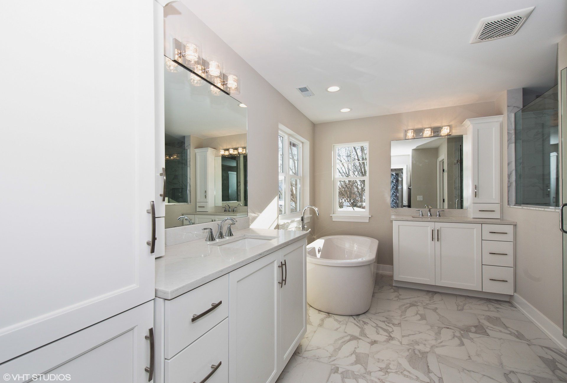 A bathroom with two sinks , a tub and a mirror.