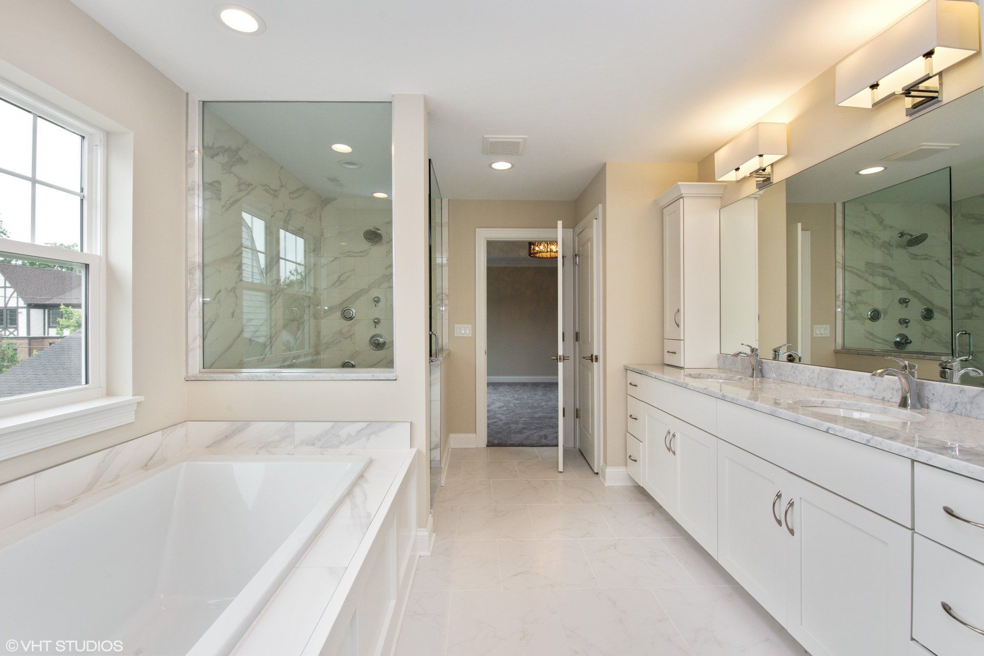 A bathroom with a tub , sinks , mirrors and a window.