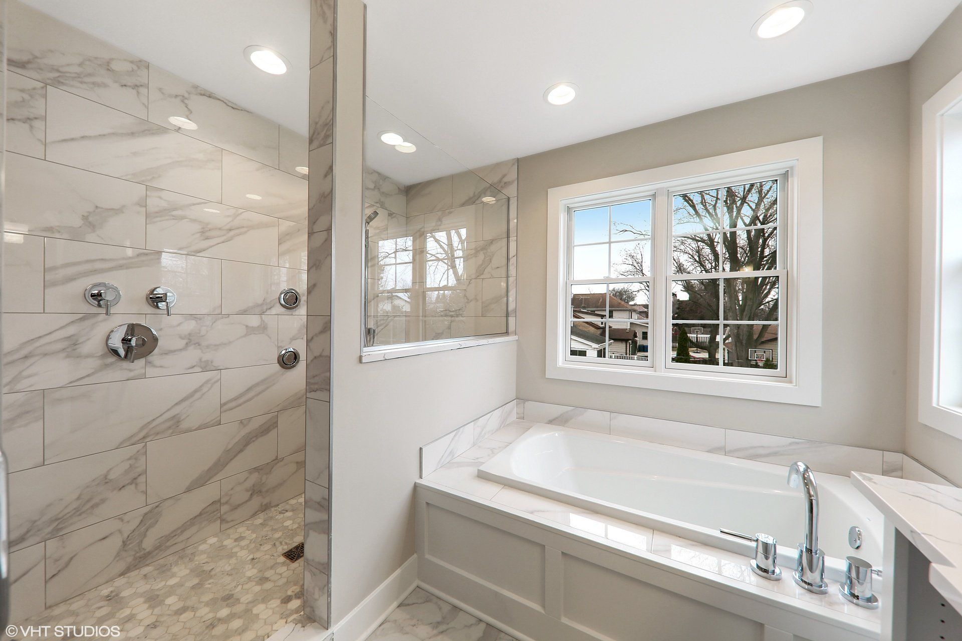 A bathroom with a tub , shower , and window.