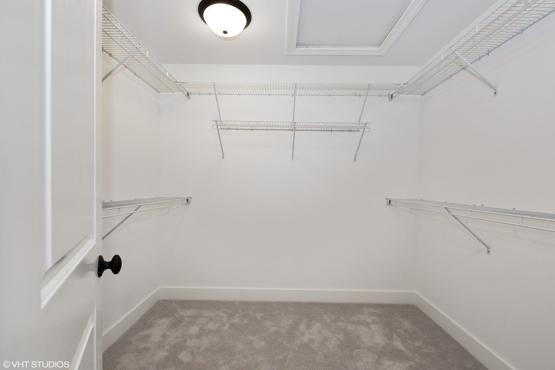 An empty walk in closet with a light on the ceiling