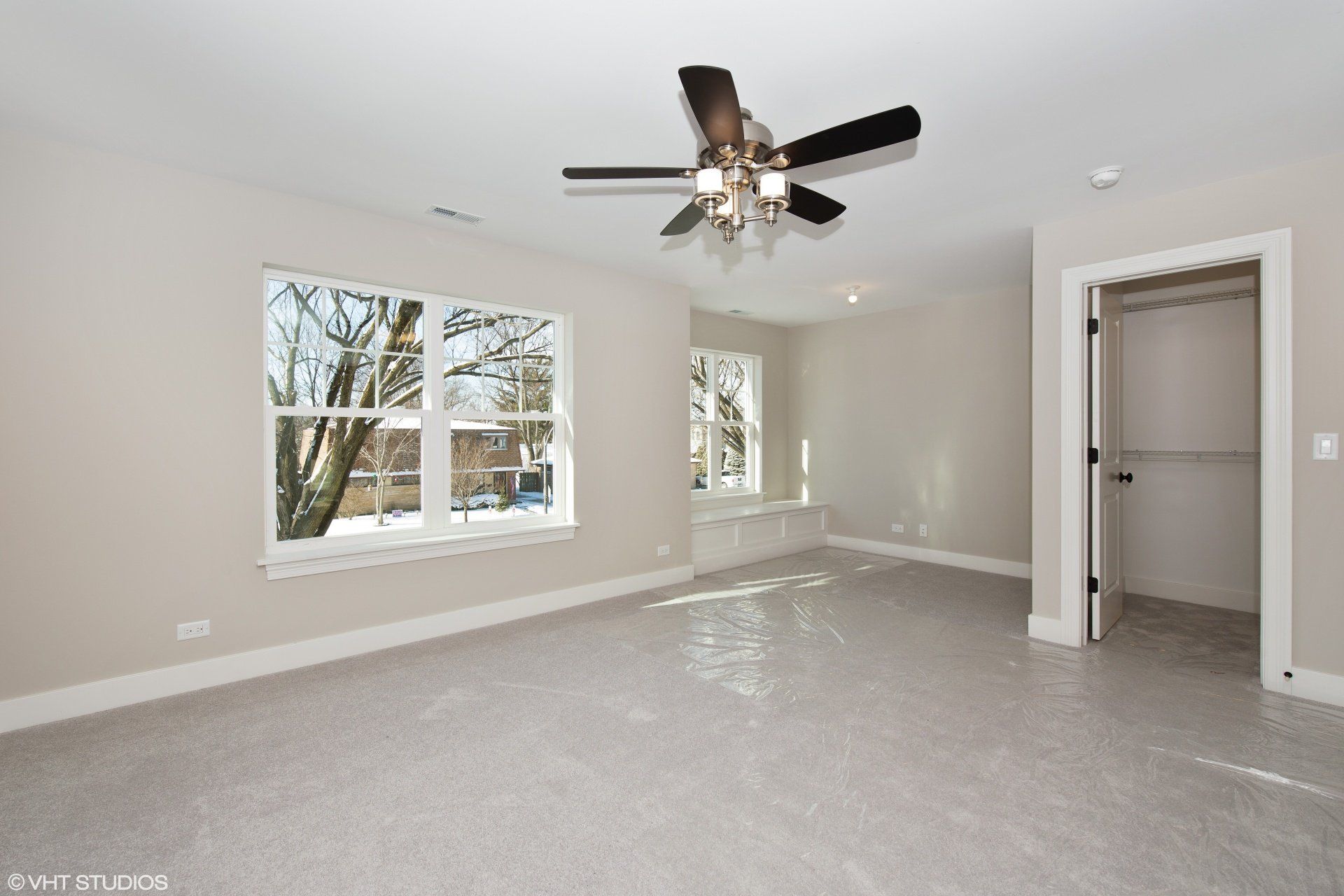 An empty bedroom with a ceiling fan and a window